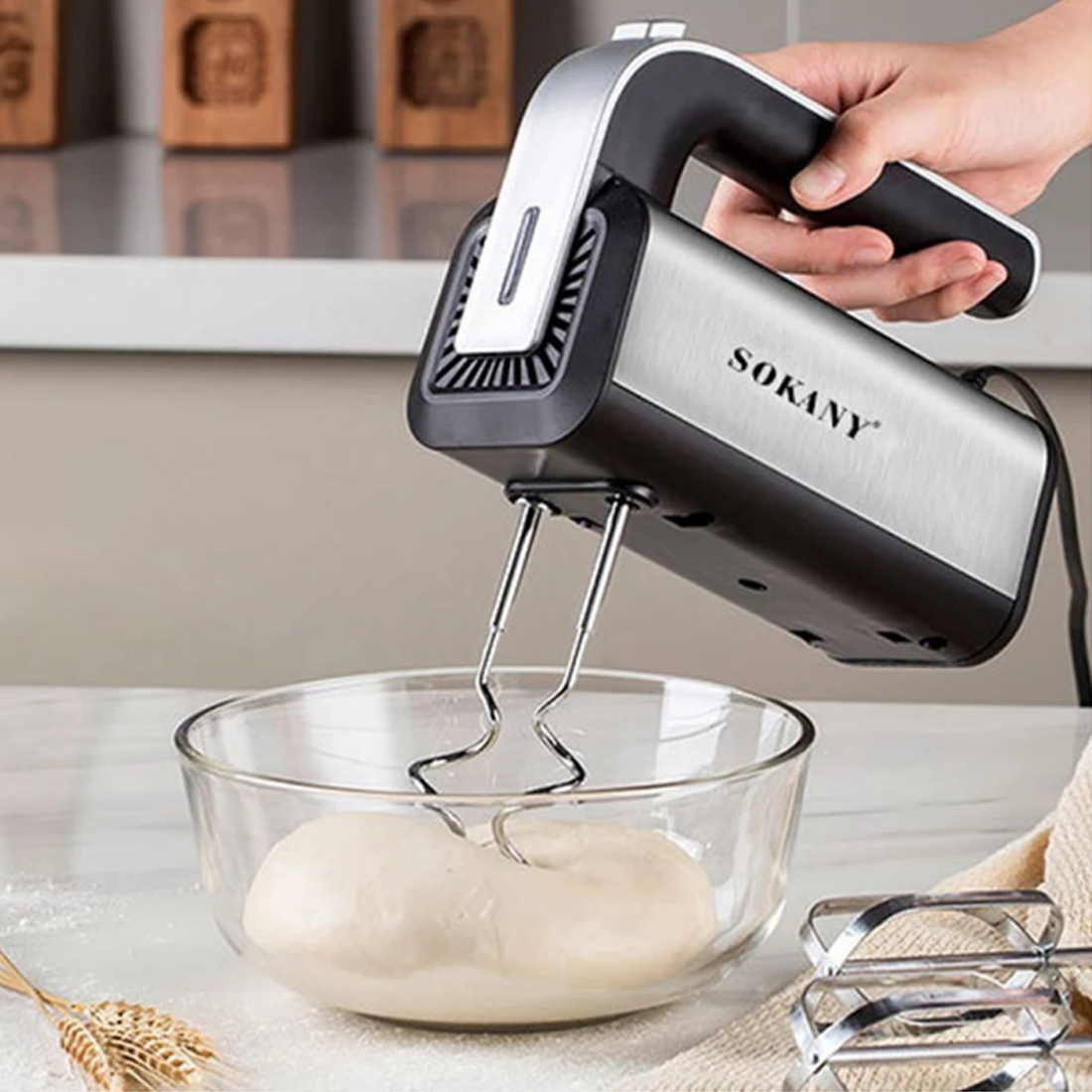 Handmixer mit Knethaken über einer Glasschüssel mit Teig.