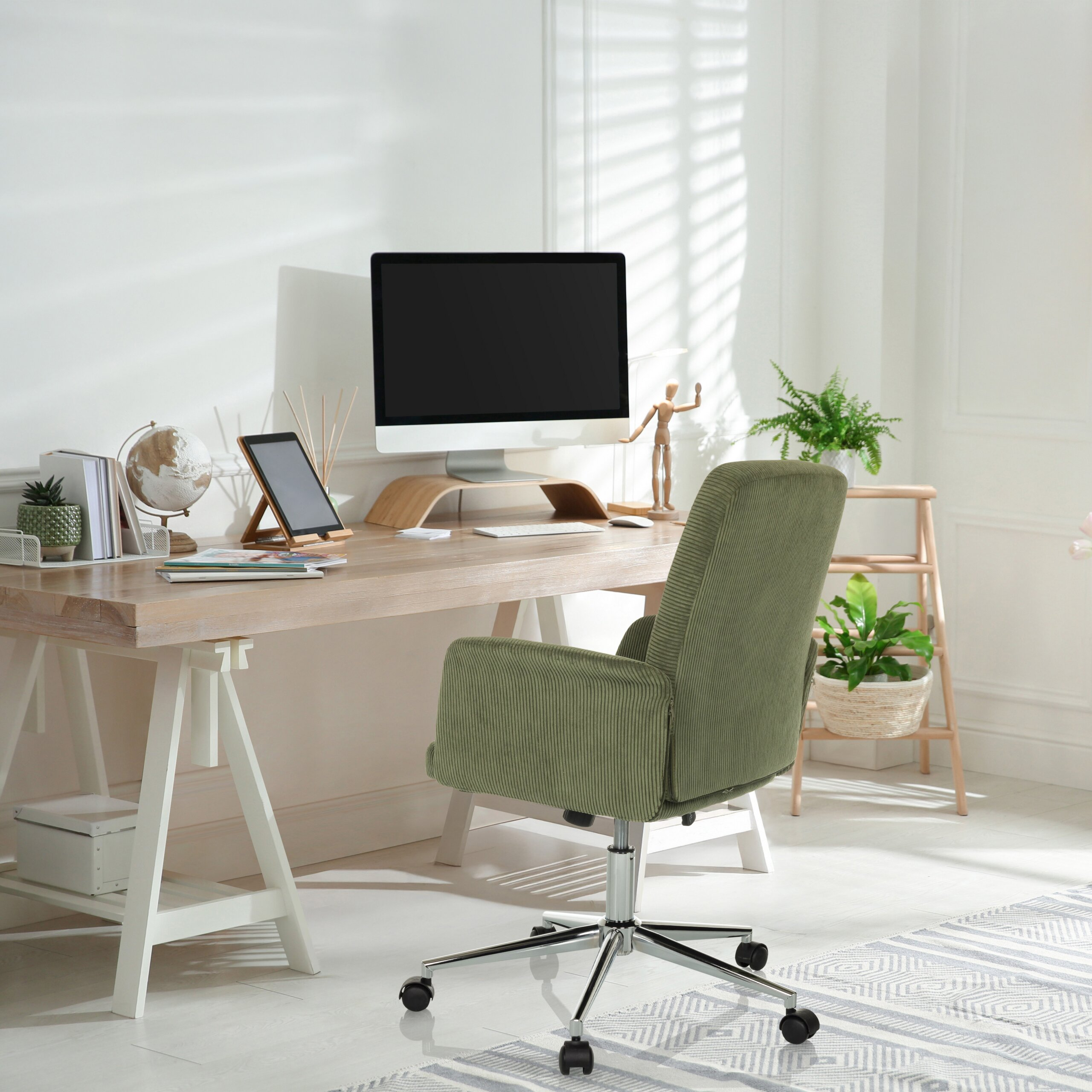 Ein helles Arbeitszimmer mit Holztisch, Computer, grünem Stuhl, Büchern, Globus und Topfpflanzen am sonnigen Fenster.
