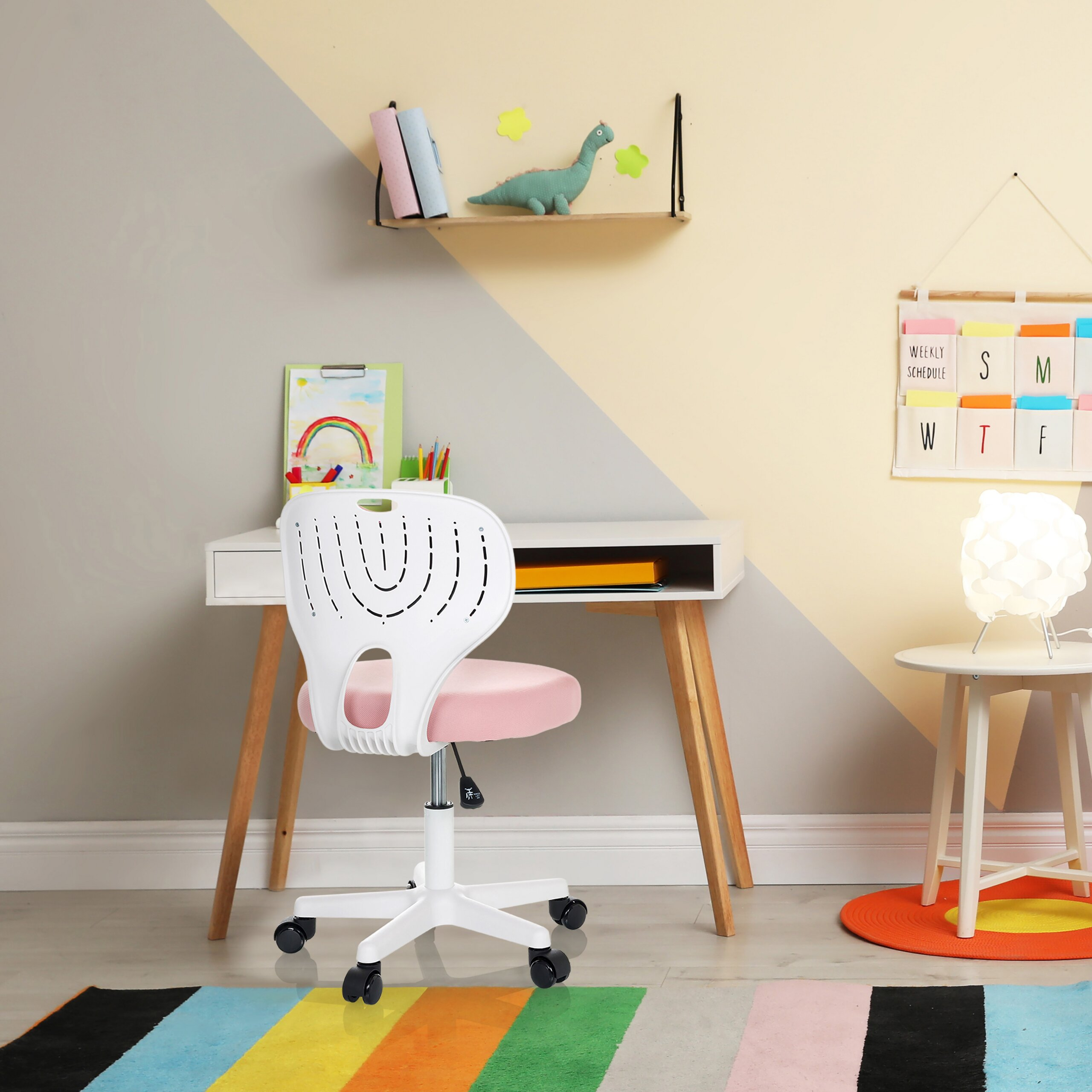 Ein weiß-rosa Kinderarbeitsstuhl steht vor einem Schreibtisch mit bunten Wänden und Regalen.