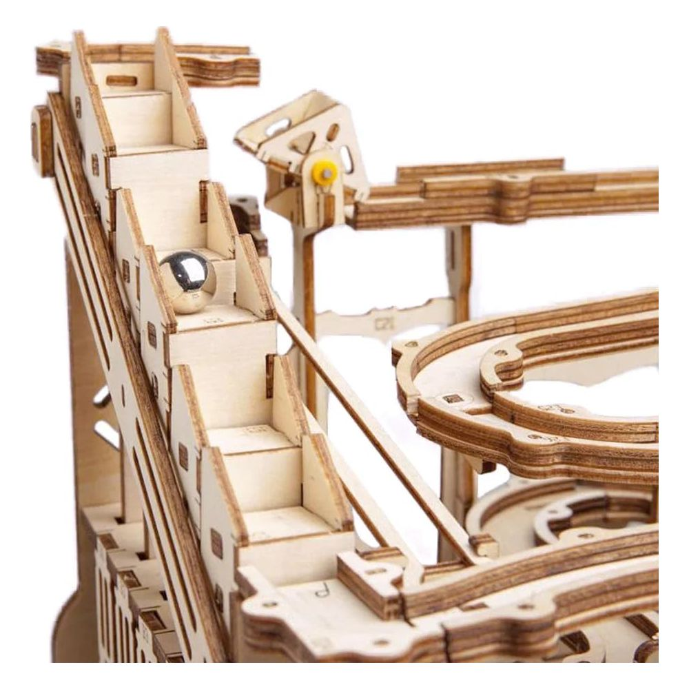 Nahaufnahme eines Holzmurmelbahn-Puzzles mit einer silbernen Metallkugel, die eine Treppe herunterrollt.