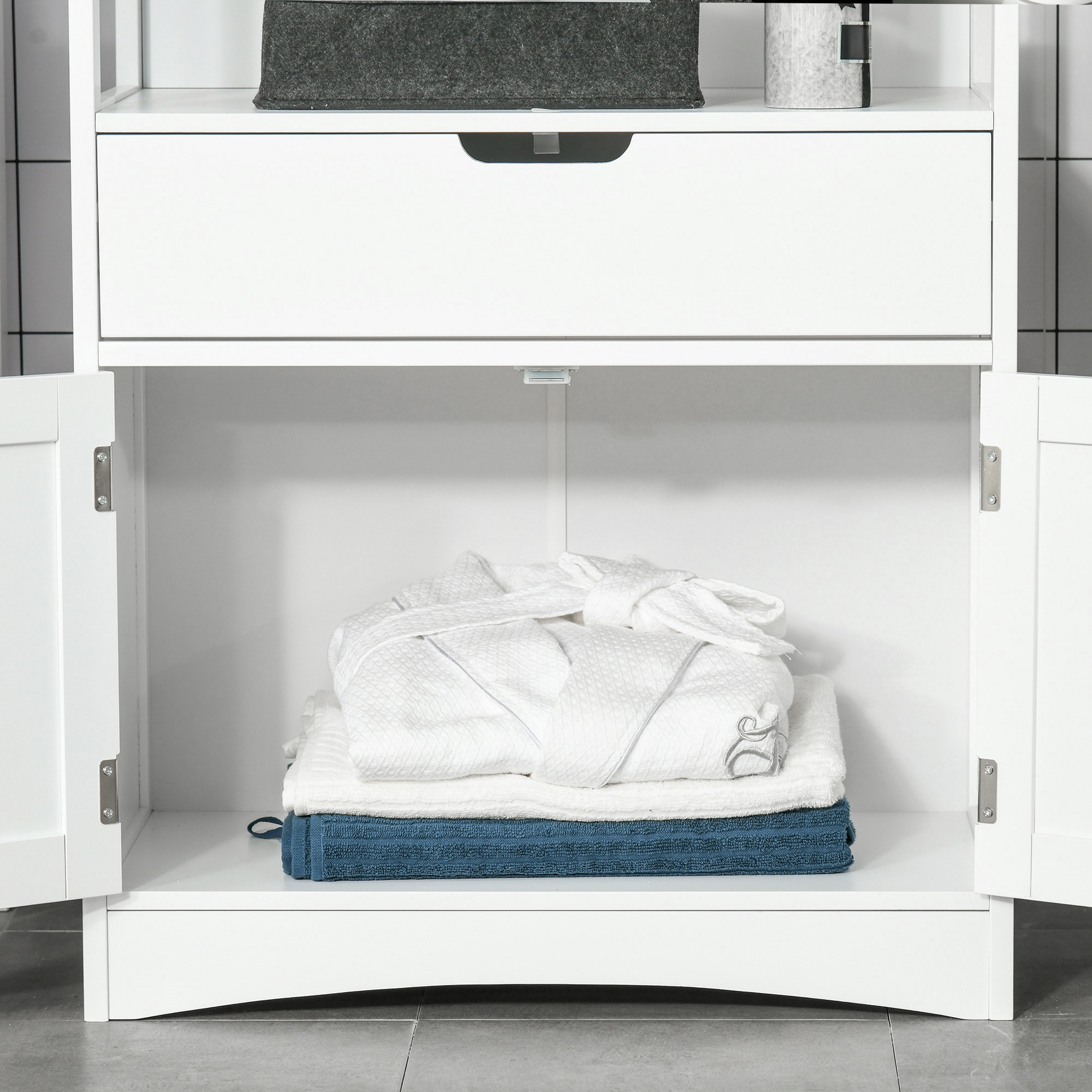 Armario de baño blanco con puertas abiertas, toallas blancas apiladas, una bata y toallas azules.