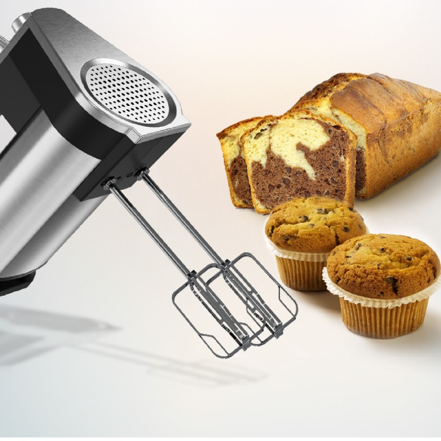 Una batidora de mano con accesorios de acero inoxidable junto a bizcocho marmolado y muffins.