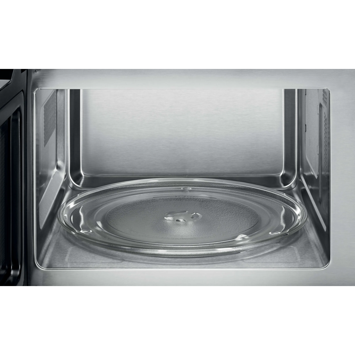 El interior de un microondas de acero inoxidable limpio con un plato giratorio de vidrio.