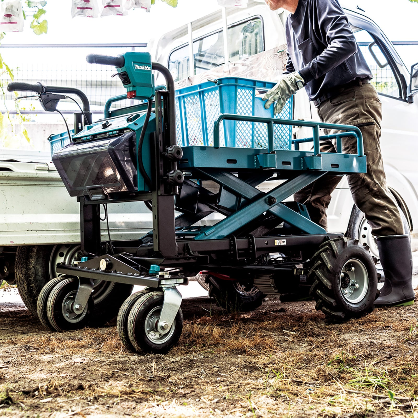 Pracownik ładuje skrzynki na elektryczny wózek podnośnikowy Makita na zewnątrz.