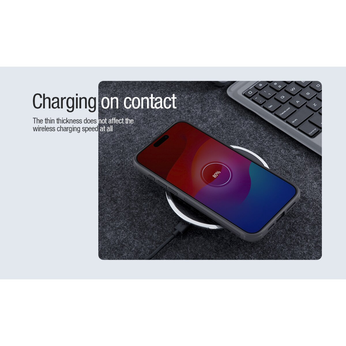 Ein Smartphone lädt kabellos auf einer Matte neben einer Tastatur, mit Text Laden bei Kontakt.