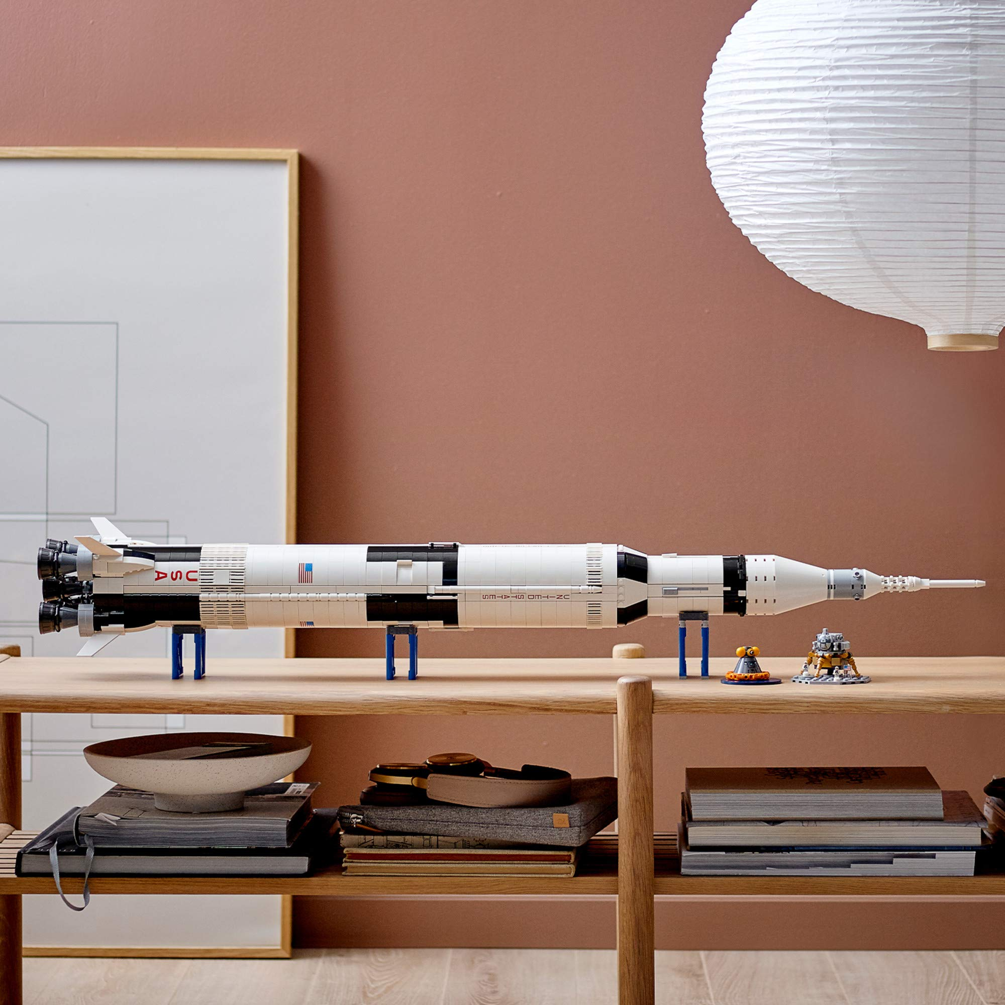 Une maquette de fusée Lego repose sur une étagère en bois.