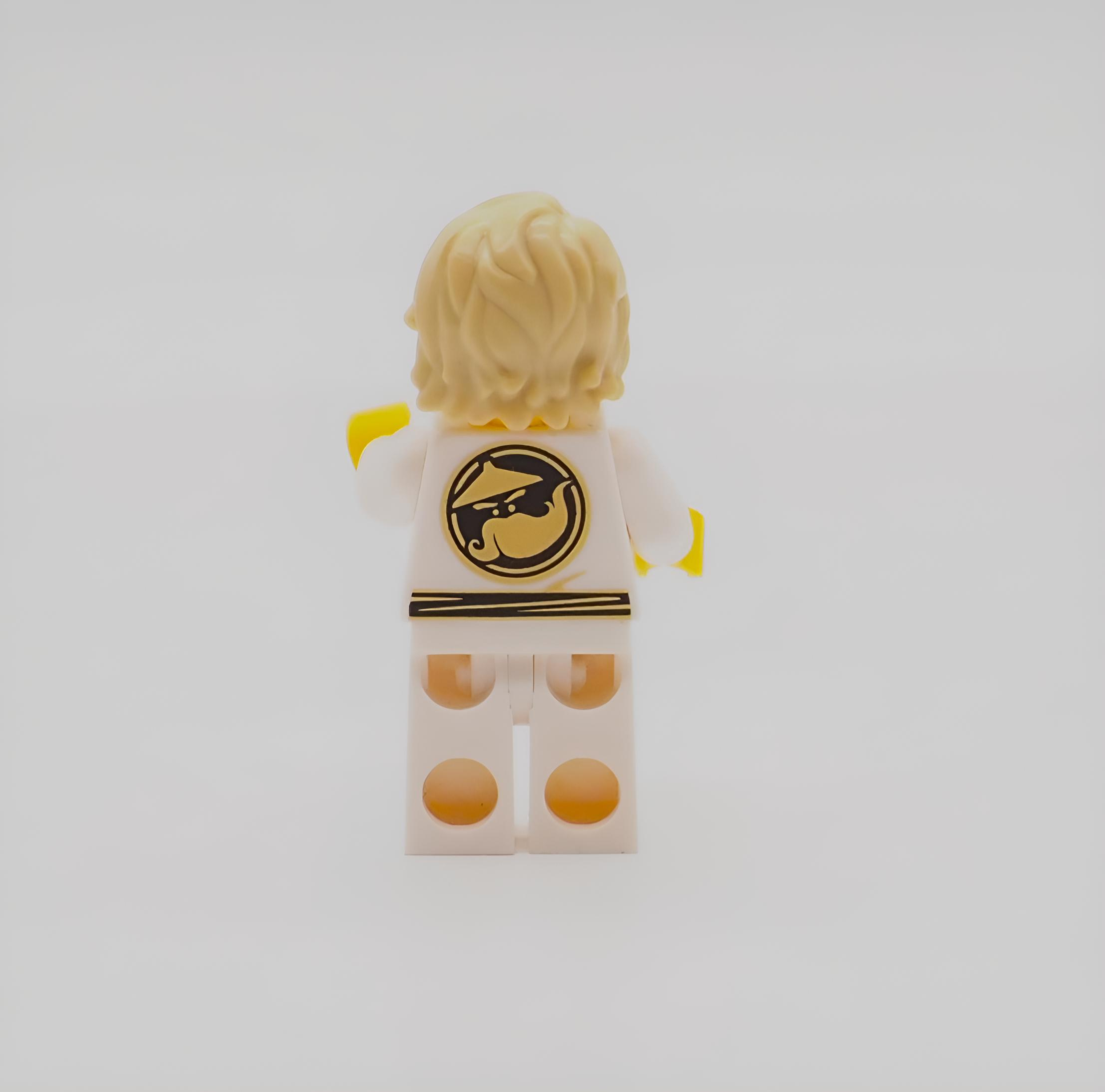Vista posteriore di una minifigure di ninja Lego bionda con abito bianco e simbolo del drago nero e oro.