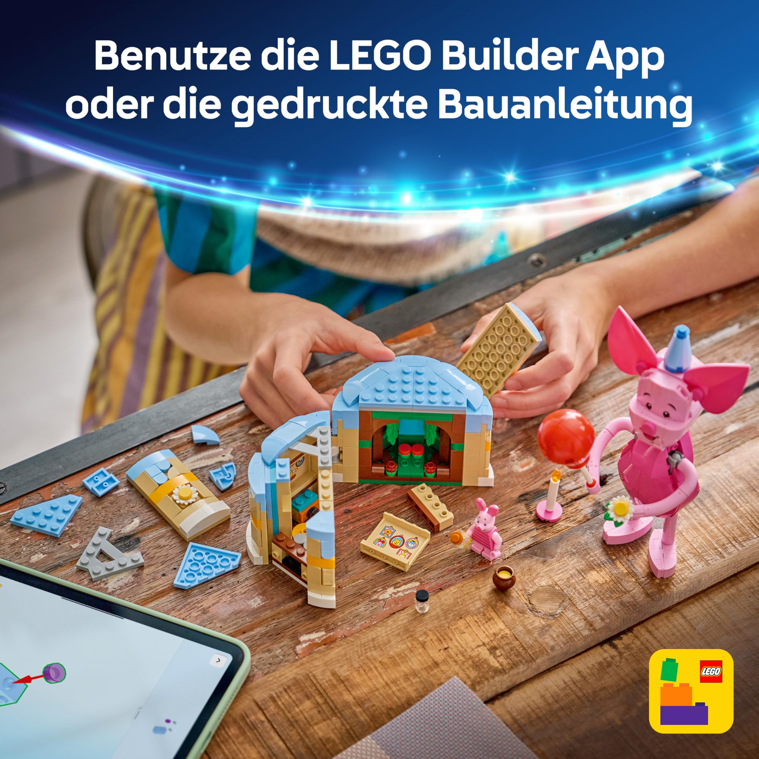 Un bambino costruisce una casa LEGO con tetti blu e un maialino rosa accanto su un tavolo di legno.