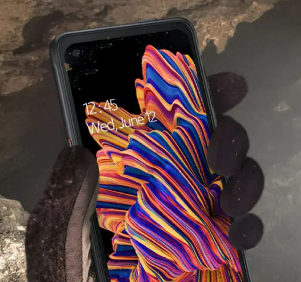 Smartphone in behandschuhten Händen zeigt buntes Wellen-Hintergrundbild mit Uhrzeit und Datum.