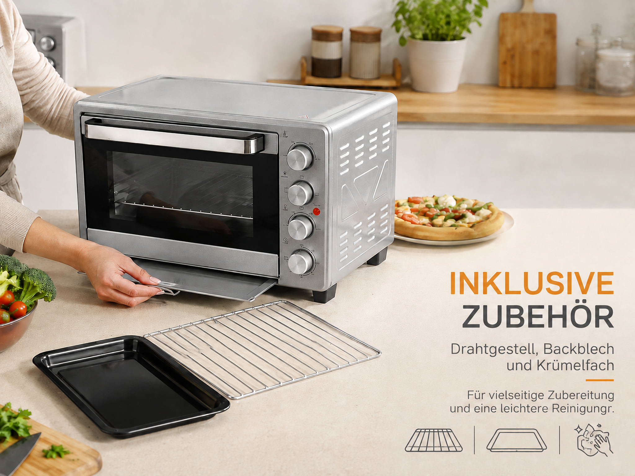 Ein silberner Mini-Ofen auf einer Küchenarbeitsplatte mit Backblech, Rost und Krümelfach.