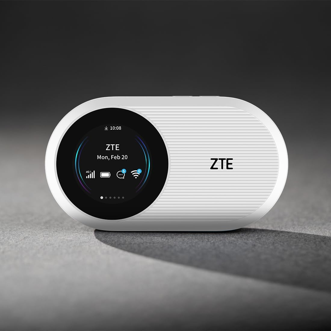 Biały przenośny router Wi-Fi ZTE z okrągłym ekranem pokazującym czas i ikony, na ciemnym tle.