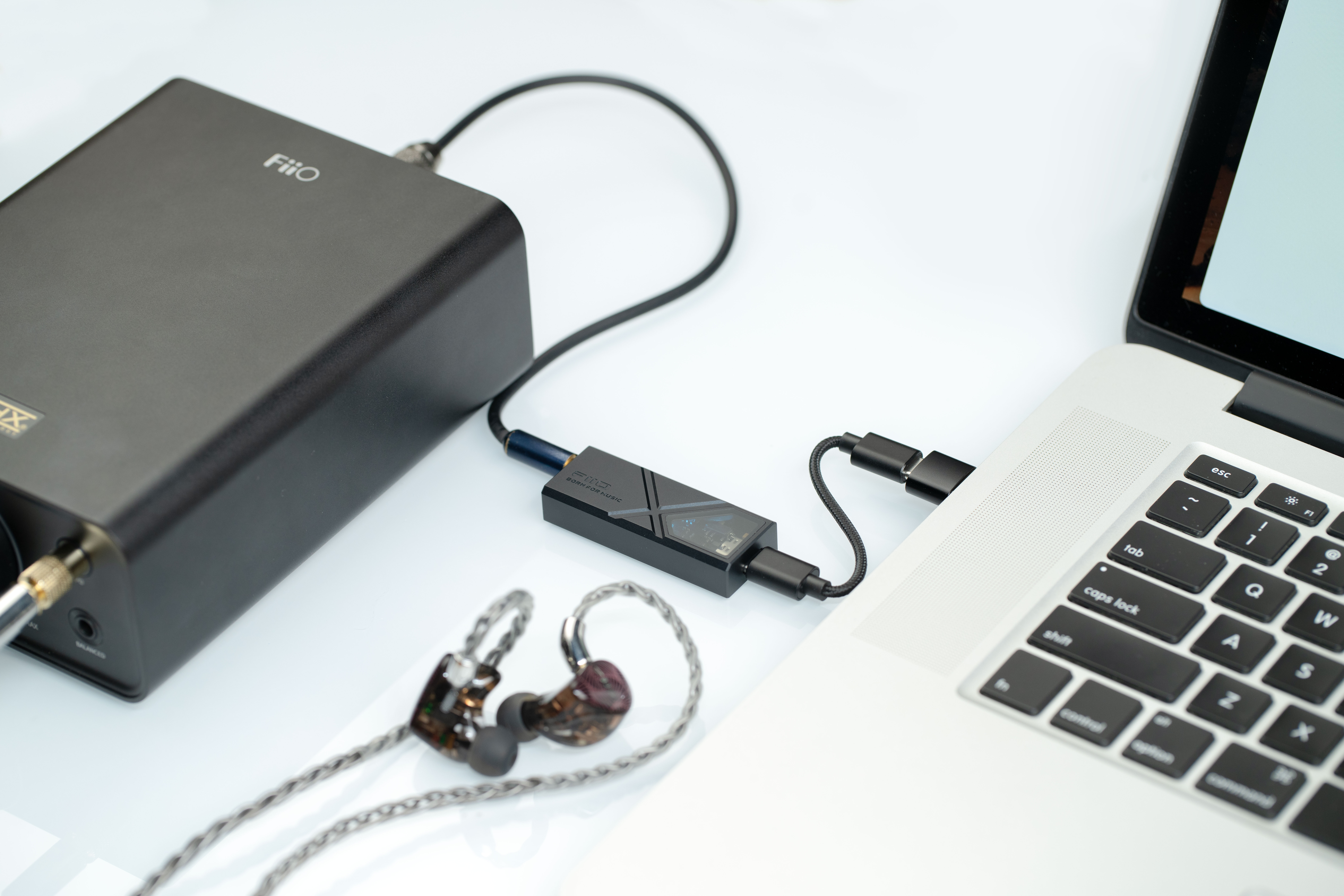Laptop jest połączony za pomocą małego wzmacniacza i kabli z dużym urządzeniem audio FiiO i słuchawkami.