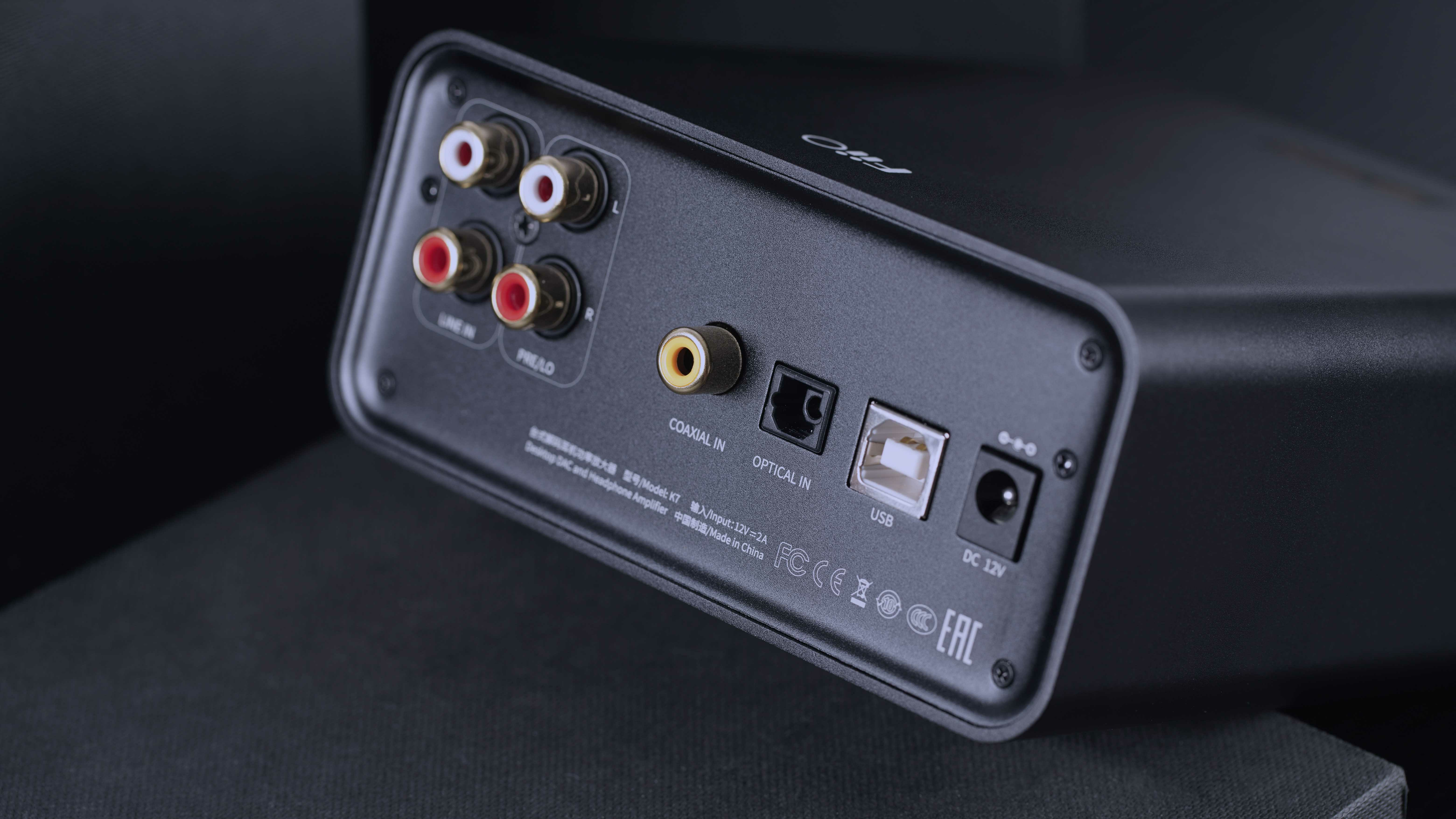 Tylny panel czarnego urządzenia audio z portami RCA, koaksjalnymi, optycznymi, USB i DC 12V.