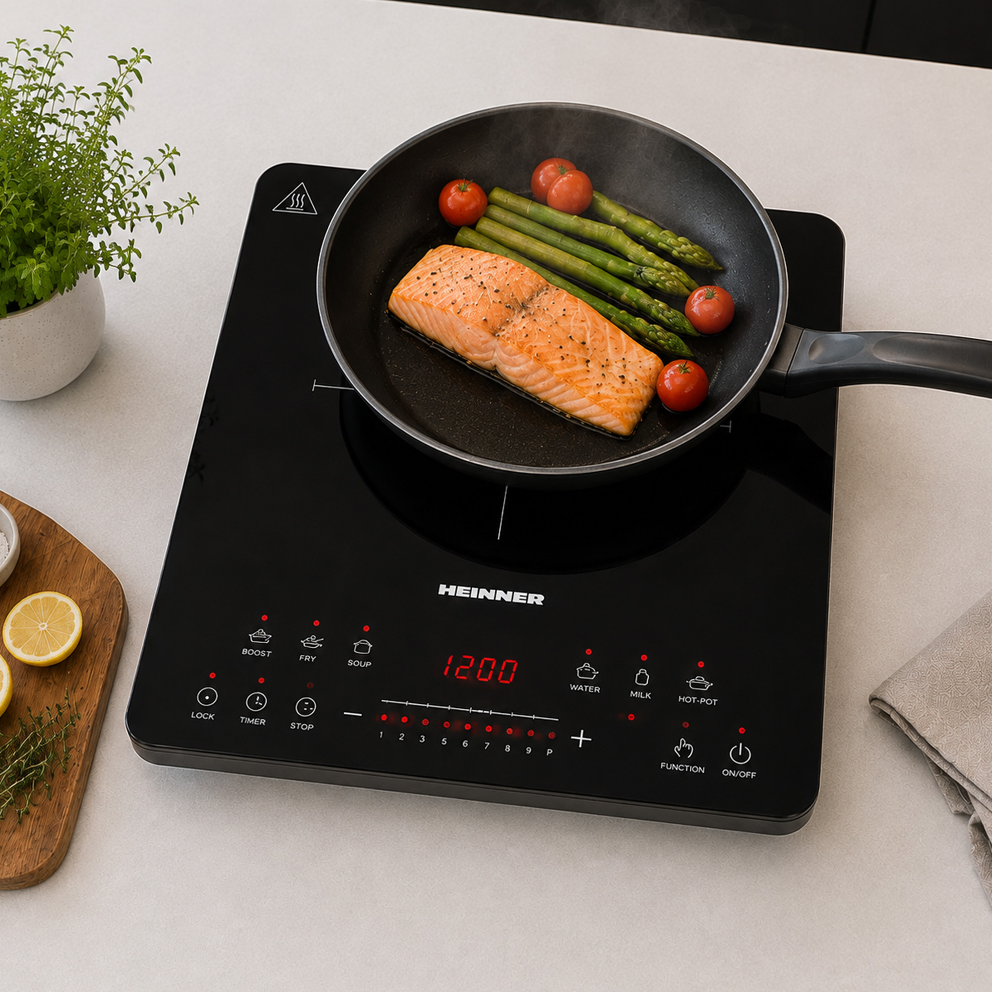 A Heinner induction cooktop with a pan containing salmon, asparagus, and tomatoes.