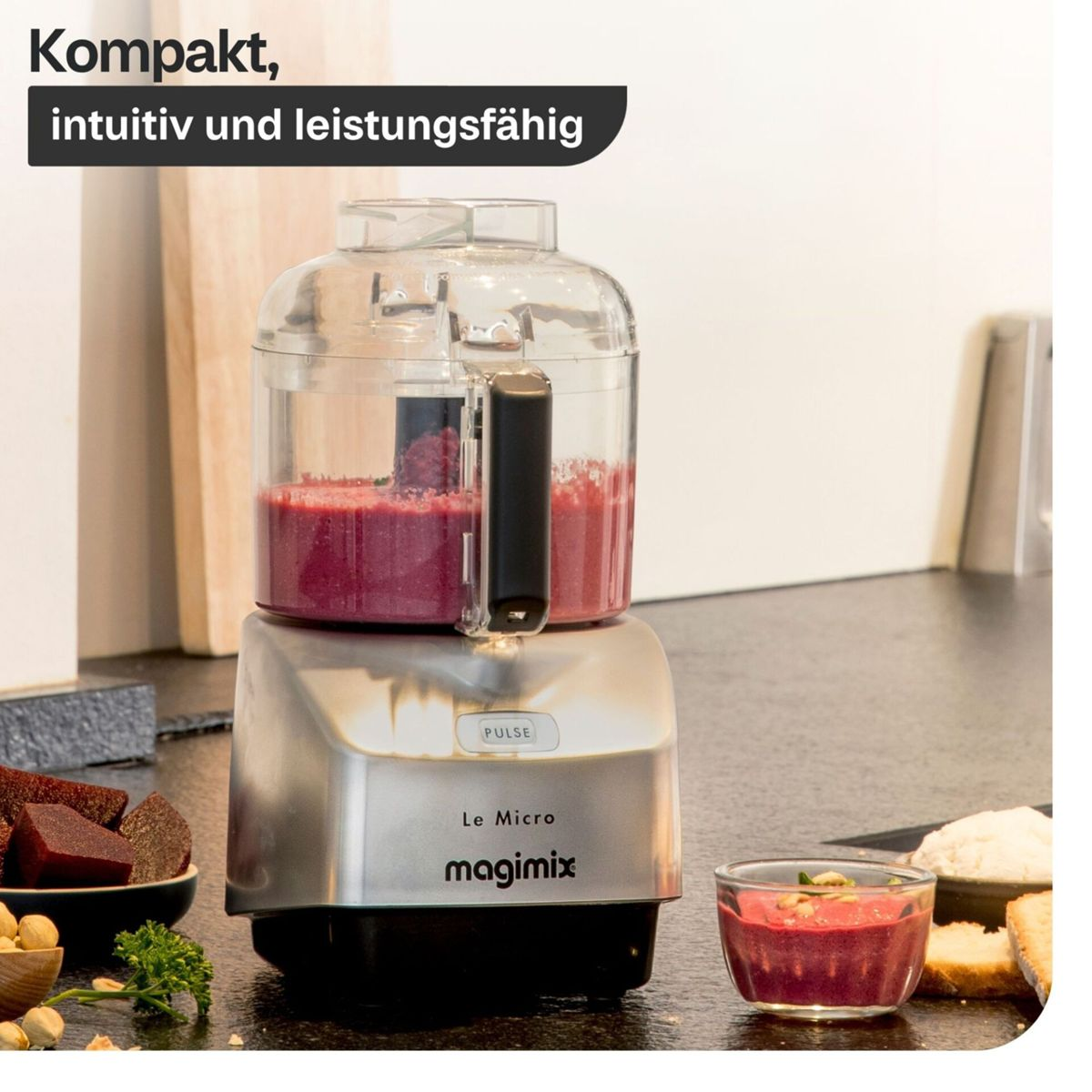 Magimix Le Micro Küchenmaschine auf einer Küchentheke mit rotem Mixgut im Behälter.