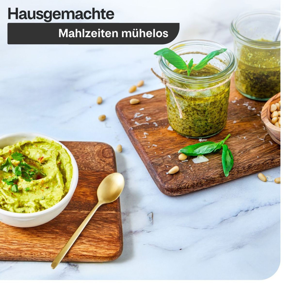 Glas Pesto, grüne Dip-Soße in einer Schüssel mit Löffel, Pinienkerne und Kräuter auf Holzbrettern.