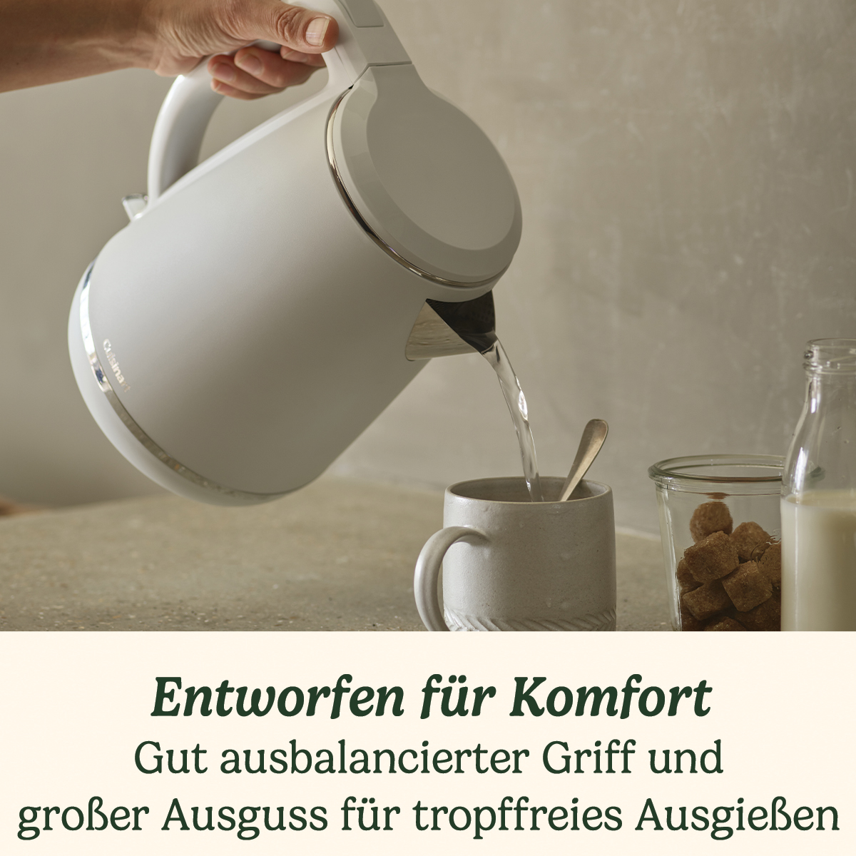 Ein weißer Wasserkocher gießt Wasser in eine Tasse auf einer hellen Küchentheke mit Zucker und Milch.