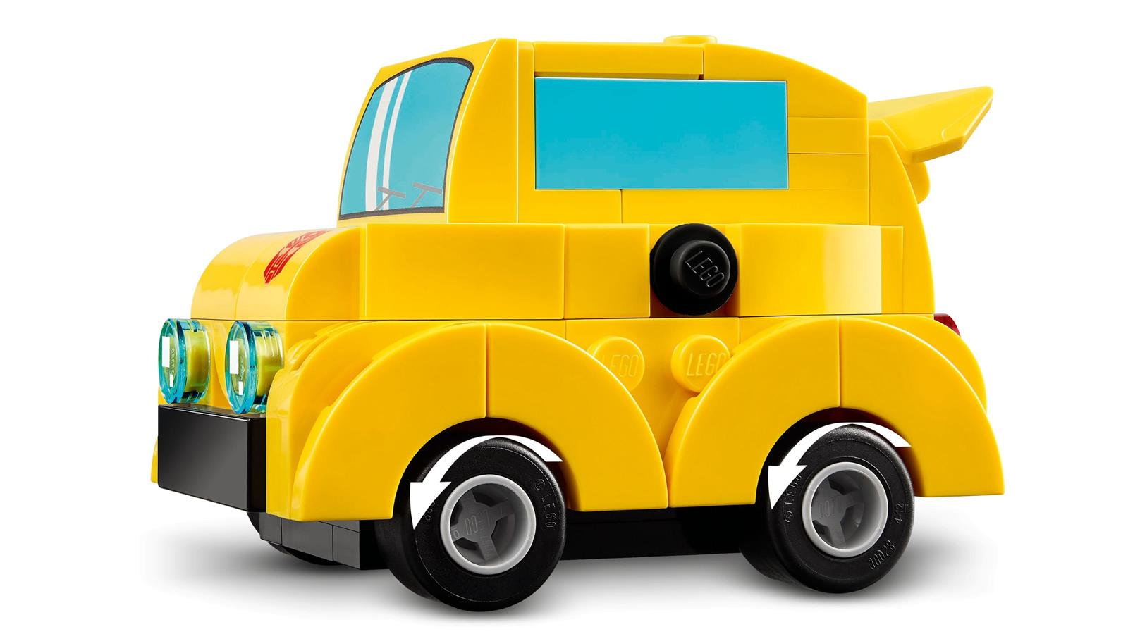 Beyaz arka planda mavi pencereli ve yuvarlak farlı sarı bir LEGO oyuncak araba.
