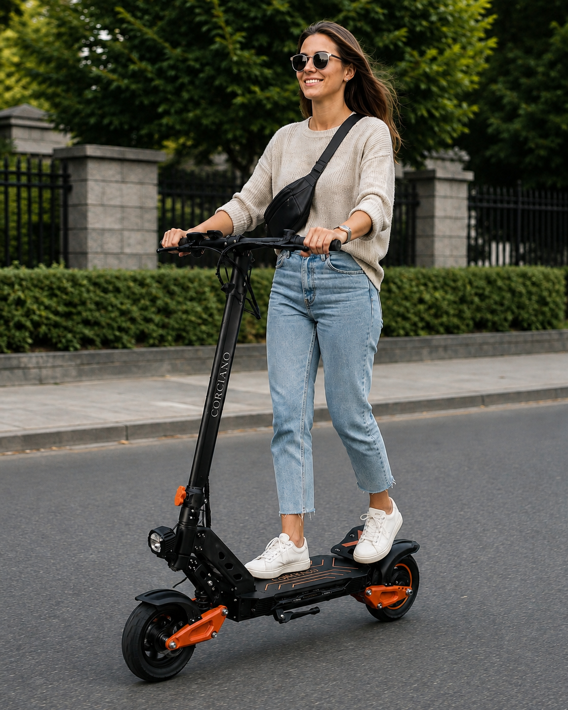 Uśmiechnięta kobieta w dżinsach i jasnym swetrze jedzie na czarnym hulajnodze elektrycznej po ulicy.