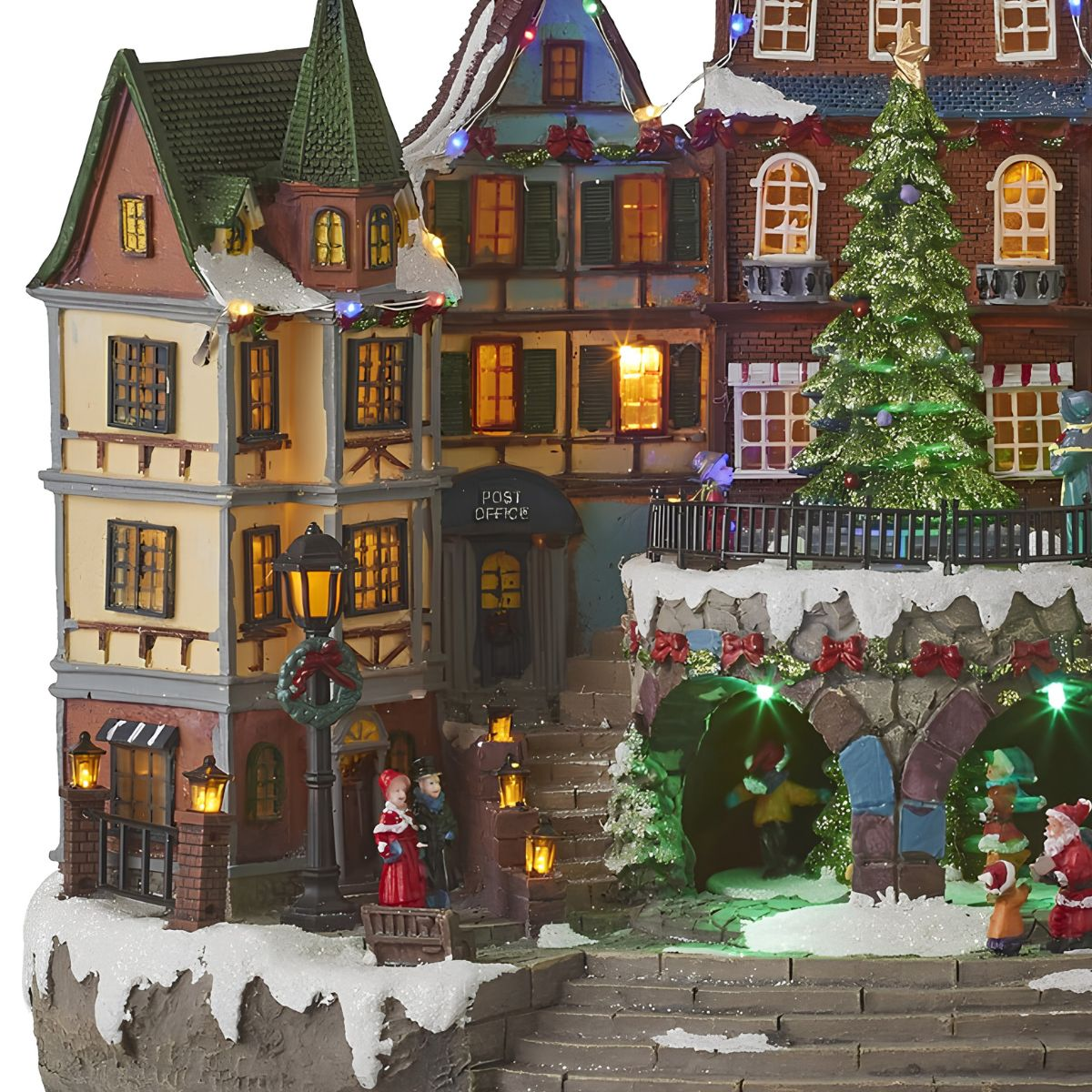 Village de Noël illuminé avec des maisons à colombages, de la neige, un grand arbre, des figurines.