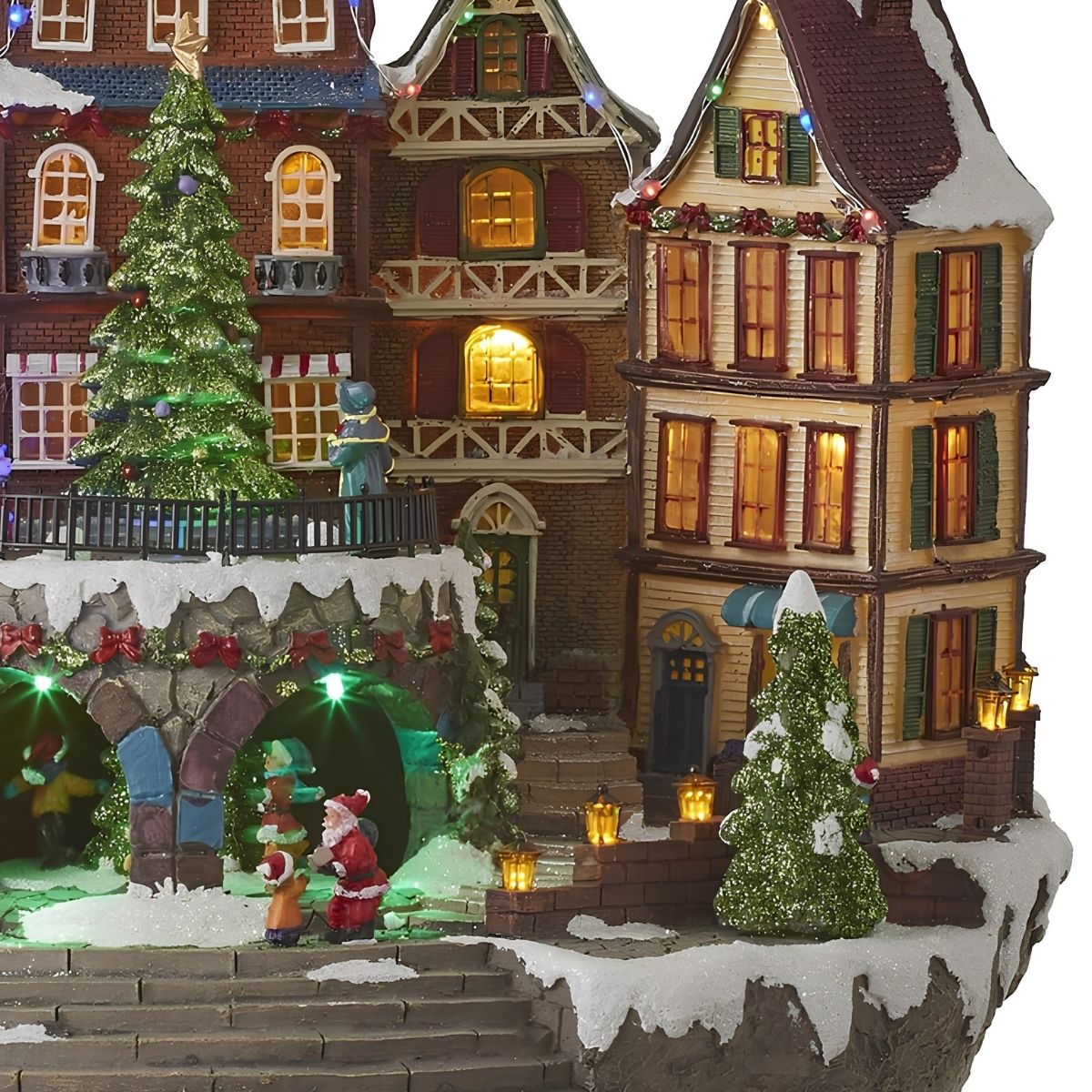 Village de Noël illuminé avec des maisons à colombages, des arbres enneigés, des figurines et des lumières.