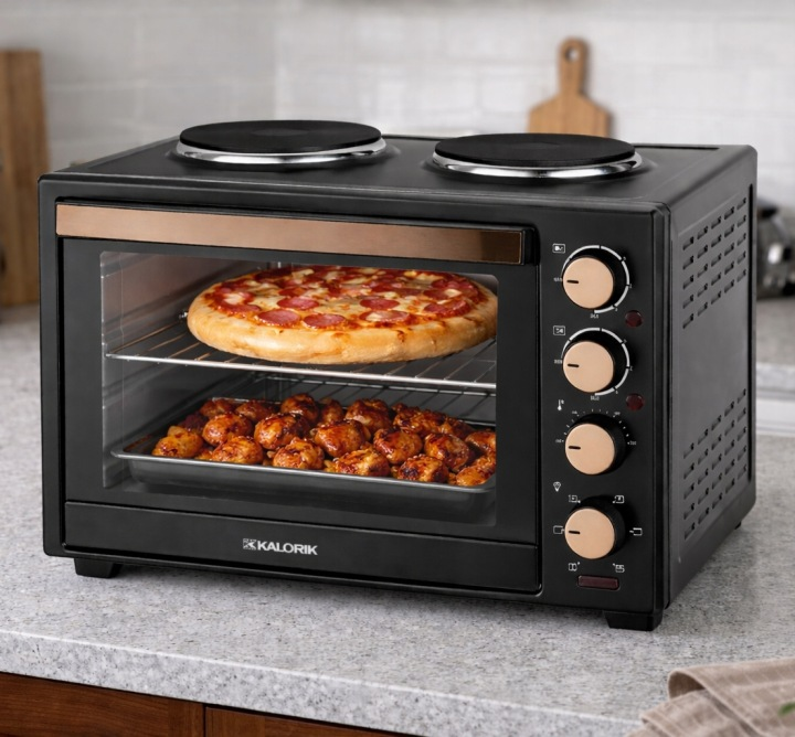 Czarny mini piekarnik Kalorik na blacie z pizzą na górze i mięsem na dole.
