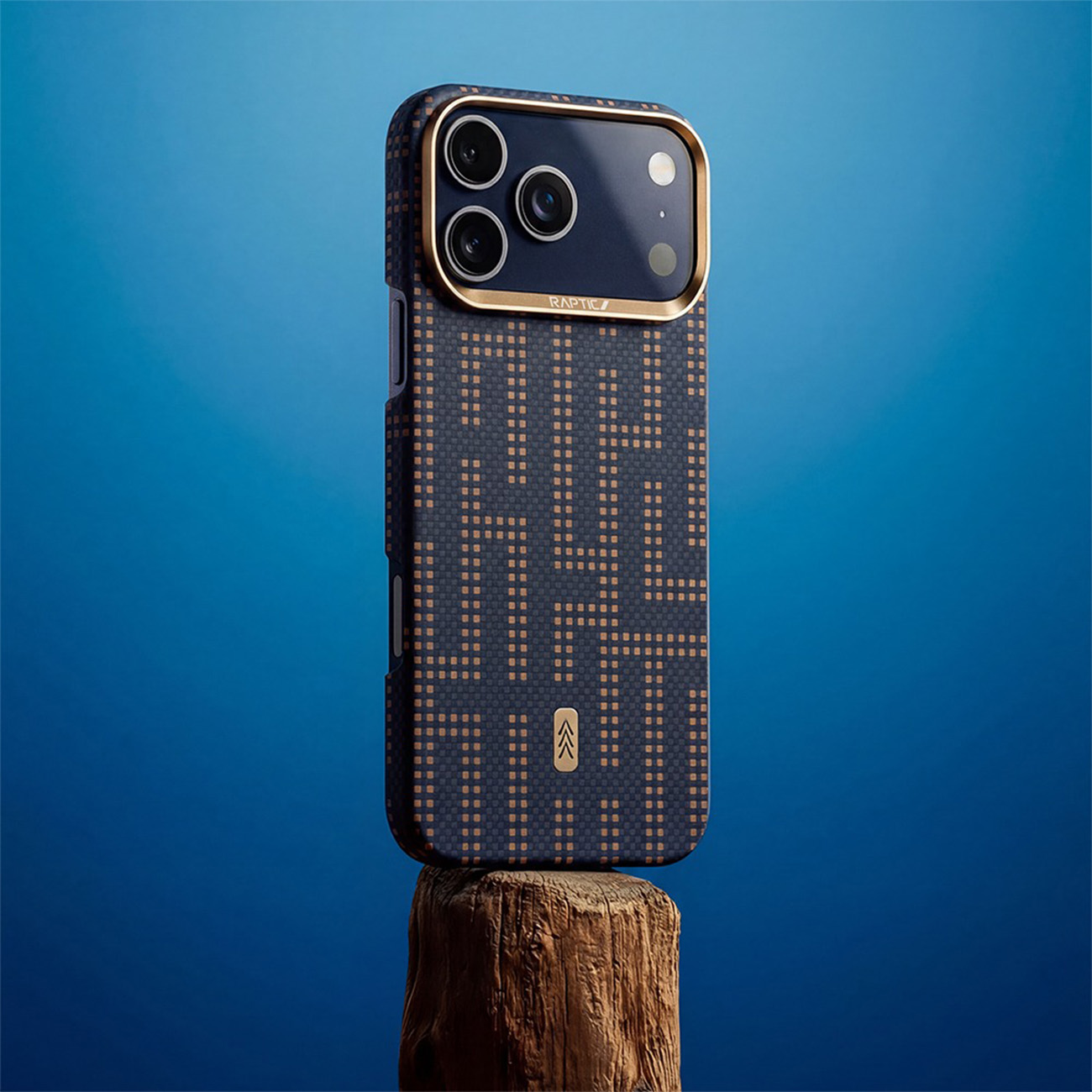 Un smartphone con funda oscura estampada y detalles dorados sobre un tocón de madera con fondo azul.