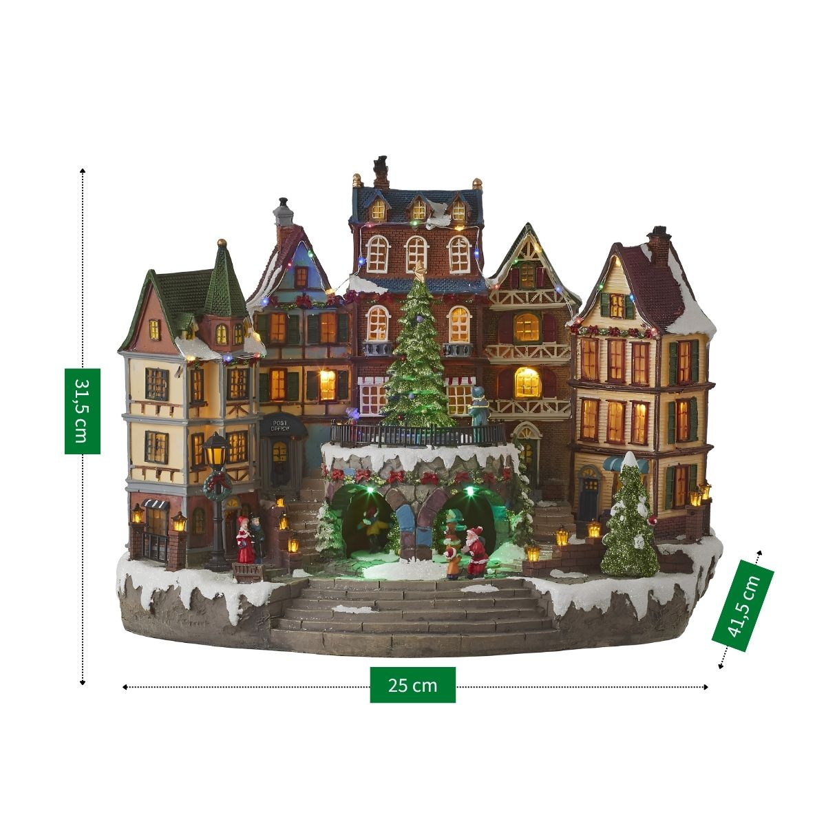 Village de Noël illuminé avec des bâtiments à plusieurs étages, un sapin décoré, de la neige et des figurines.