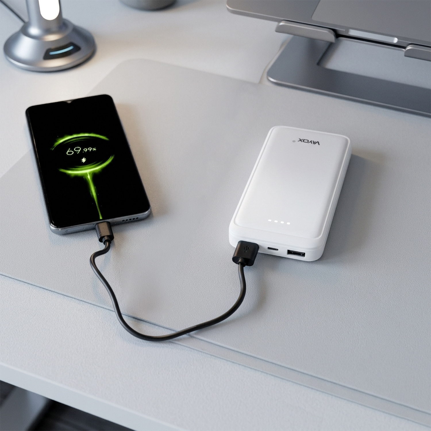 Czarny smartfon ładuje się z białego powerbanka na podkładce na biurko.