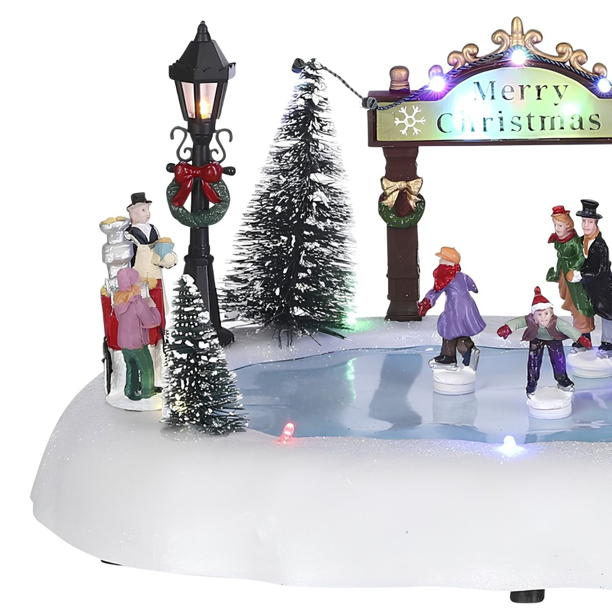 Une figurine de village de Noël festive montre des gens faisant du patin à glace sur un étang gelé sous un panneau lumineux.