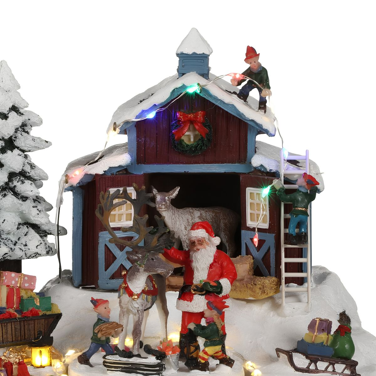 Scène de village de Noël avec le Père Noël, des rennes, des lutins et une grange rouge.