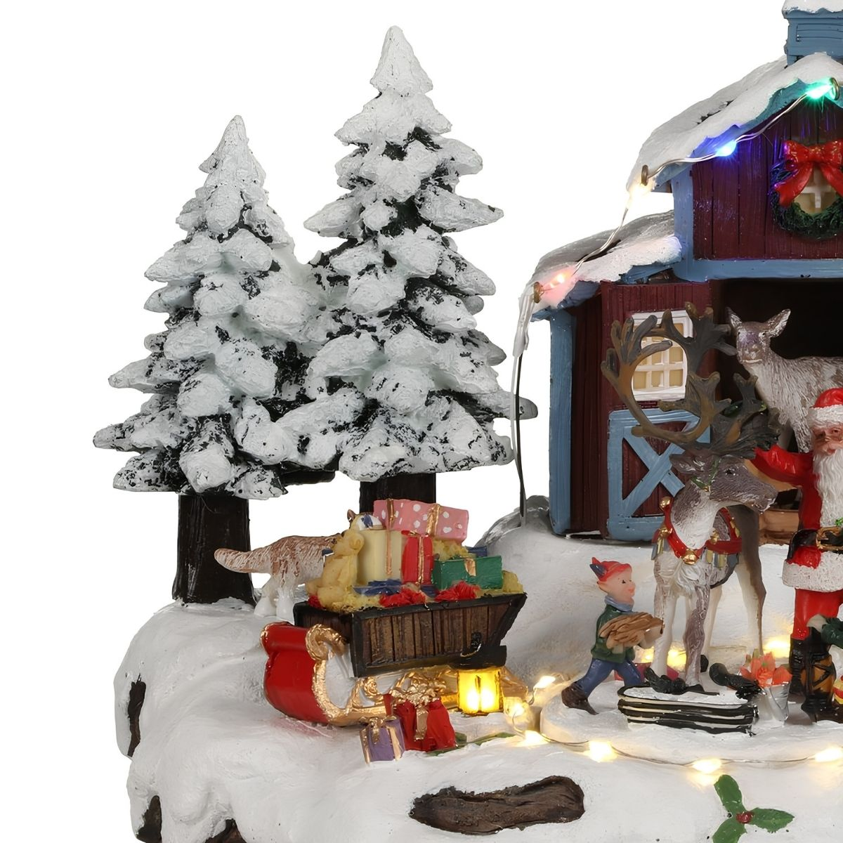 Une scène de Noël enneigée avec une grange rouge, le Père Noël, des rennes, un traîneau de cadeaux et des sapins.