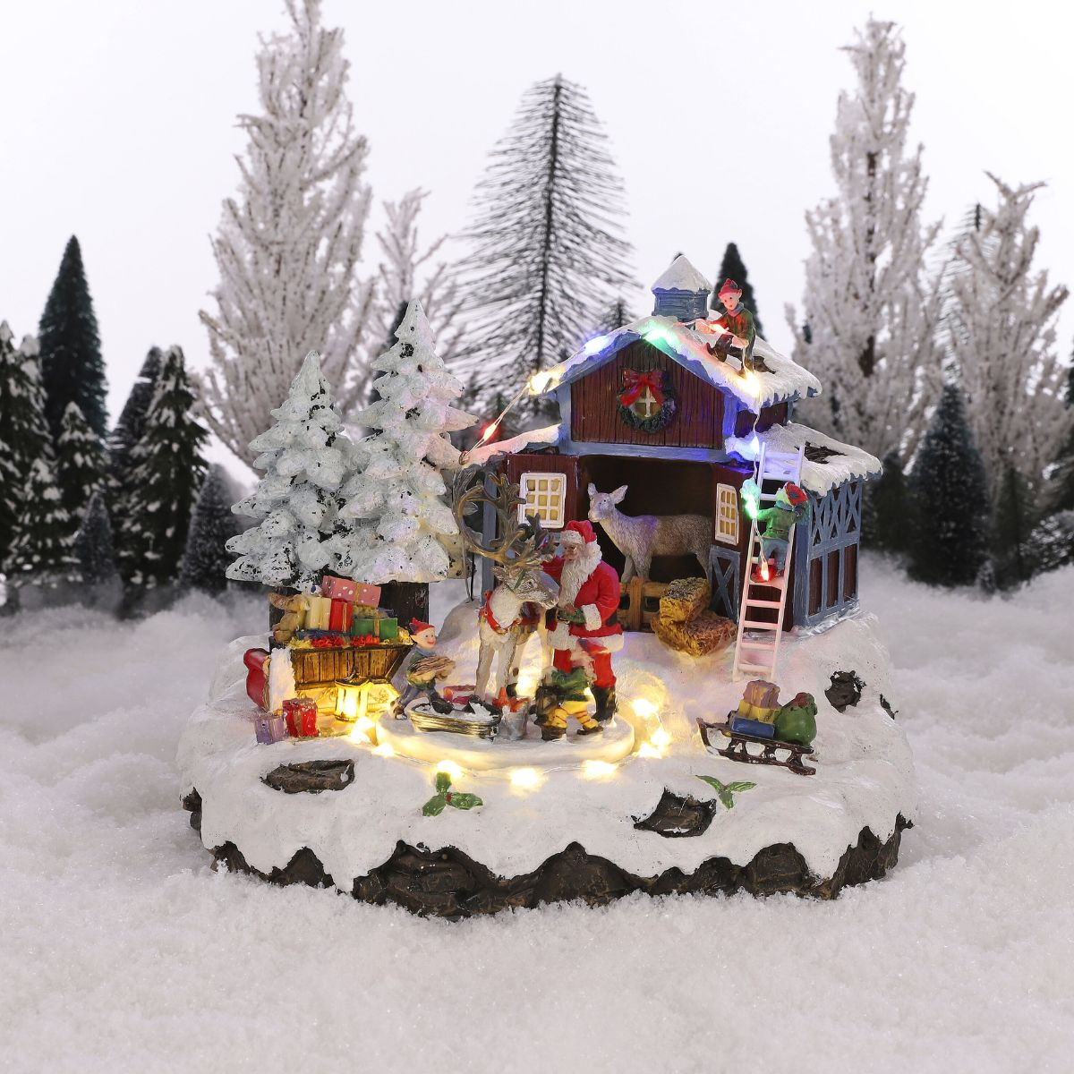 Une figurine de village de Noël avec le Père Noël, des rennes et des sapins.