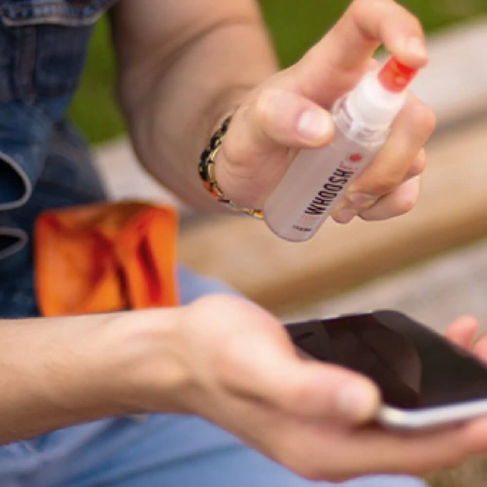 Ręka spryskuje płynem czyszczącym smartfon.