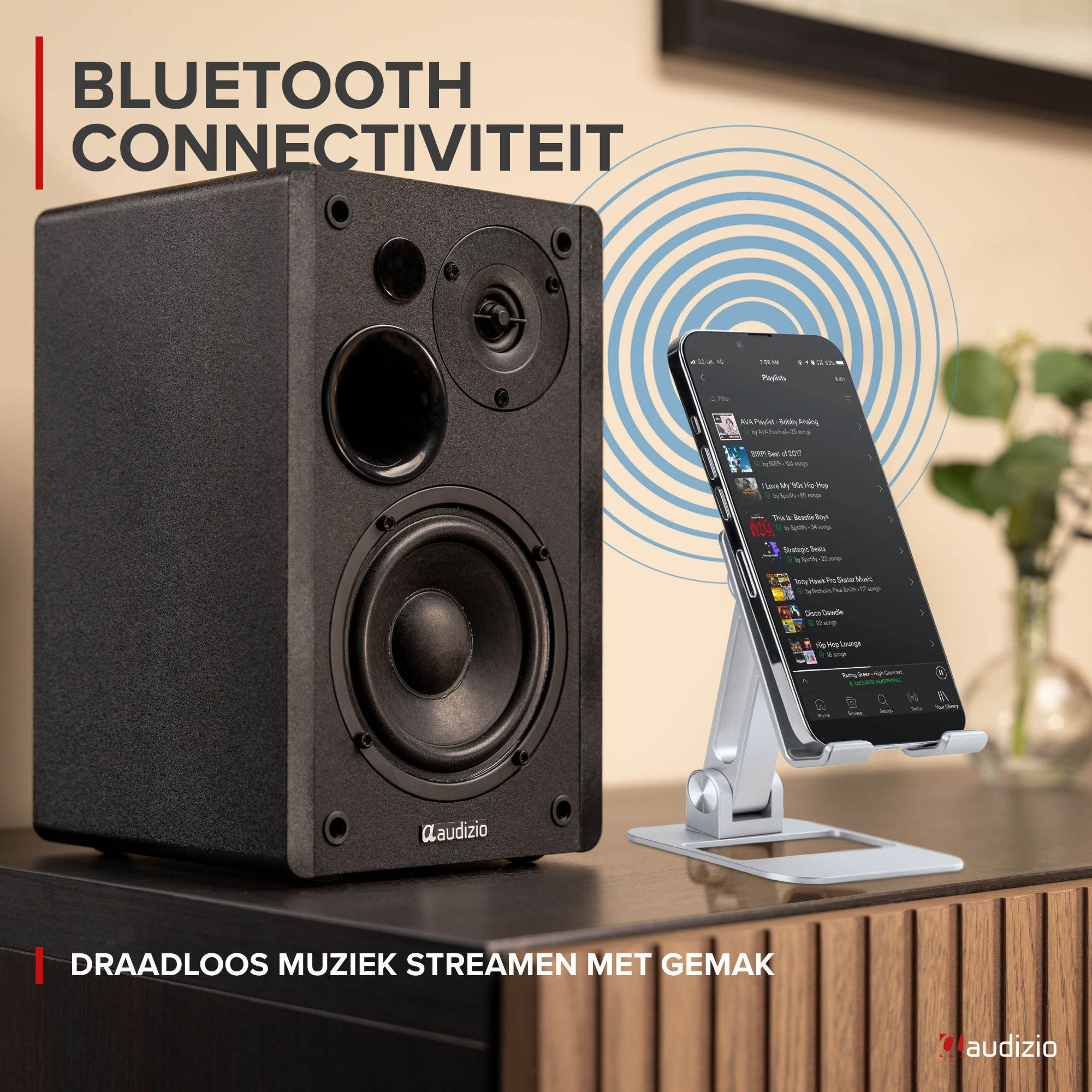 Un altavoz negro Audizio al lado de un smartphone en un soporte, transmitiendo música.