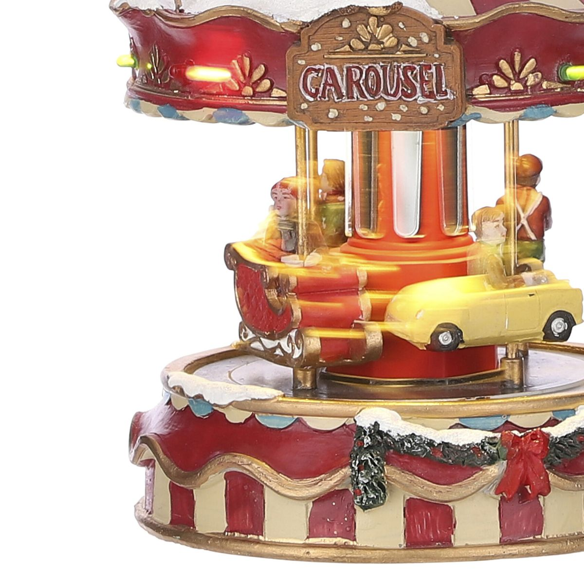 Een verlichte rode kerstcarrousel met figuren in sleeën en auto's, op een met sneeuw bedekte voet.