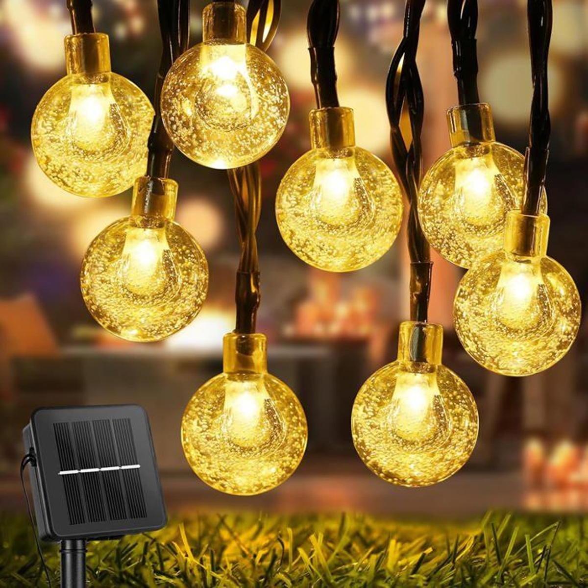 Leuchtende Lichterkette mit Blblasenkugeln über einem Solarmodul auf Gras.