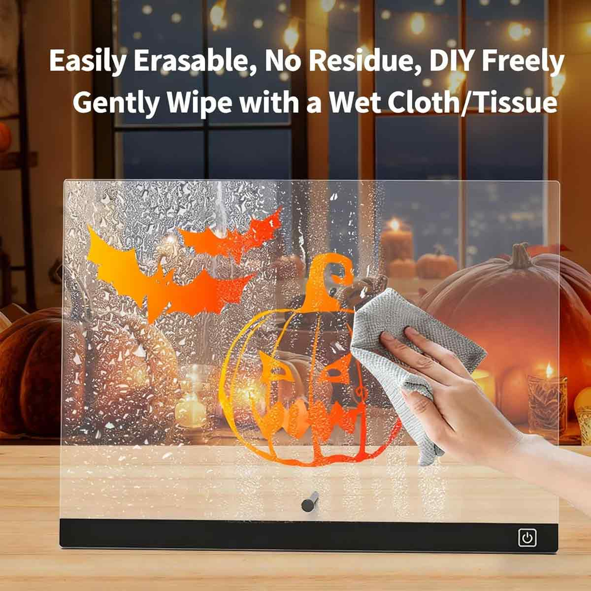 Eine Hand wischt ein leuchtendes Acrylbrett mit Halloween-Motiven ab.