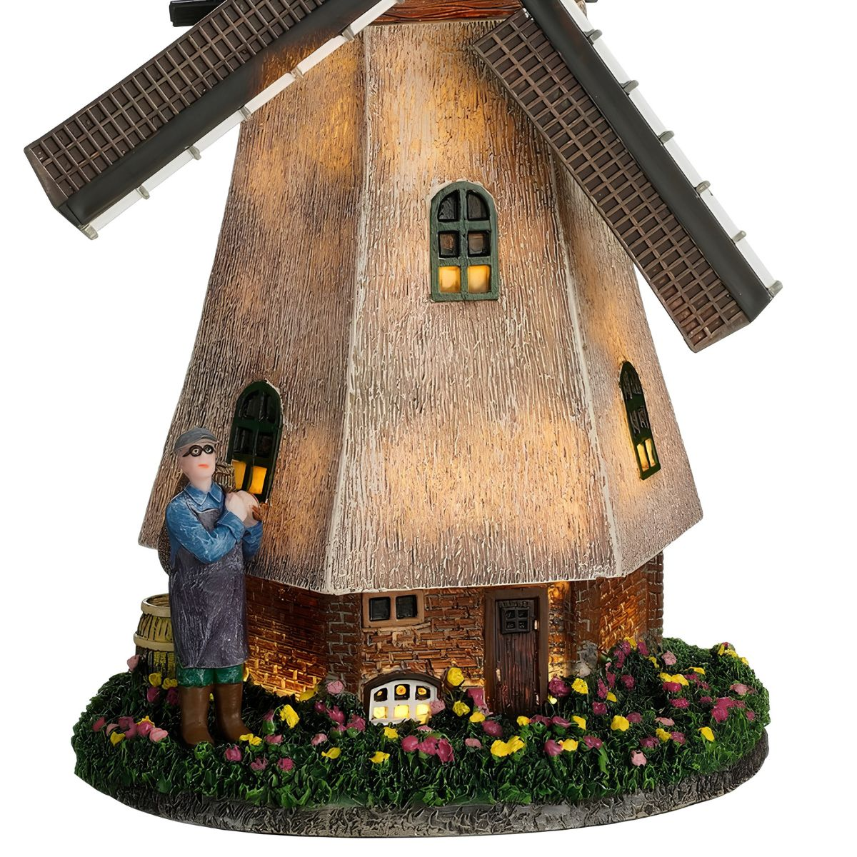 Model van een verlichte rieten molen met een figuur op de voorgrond en bloemen.