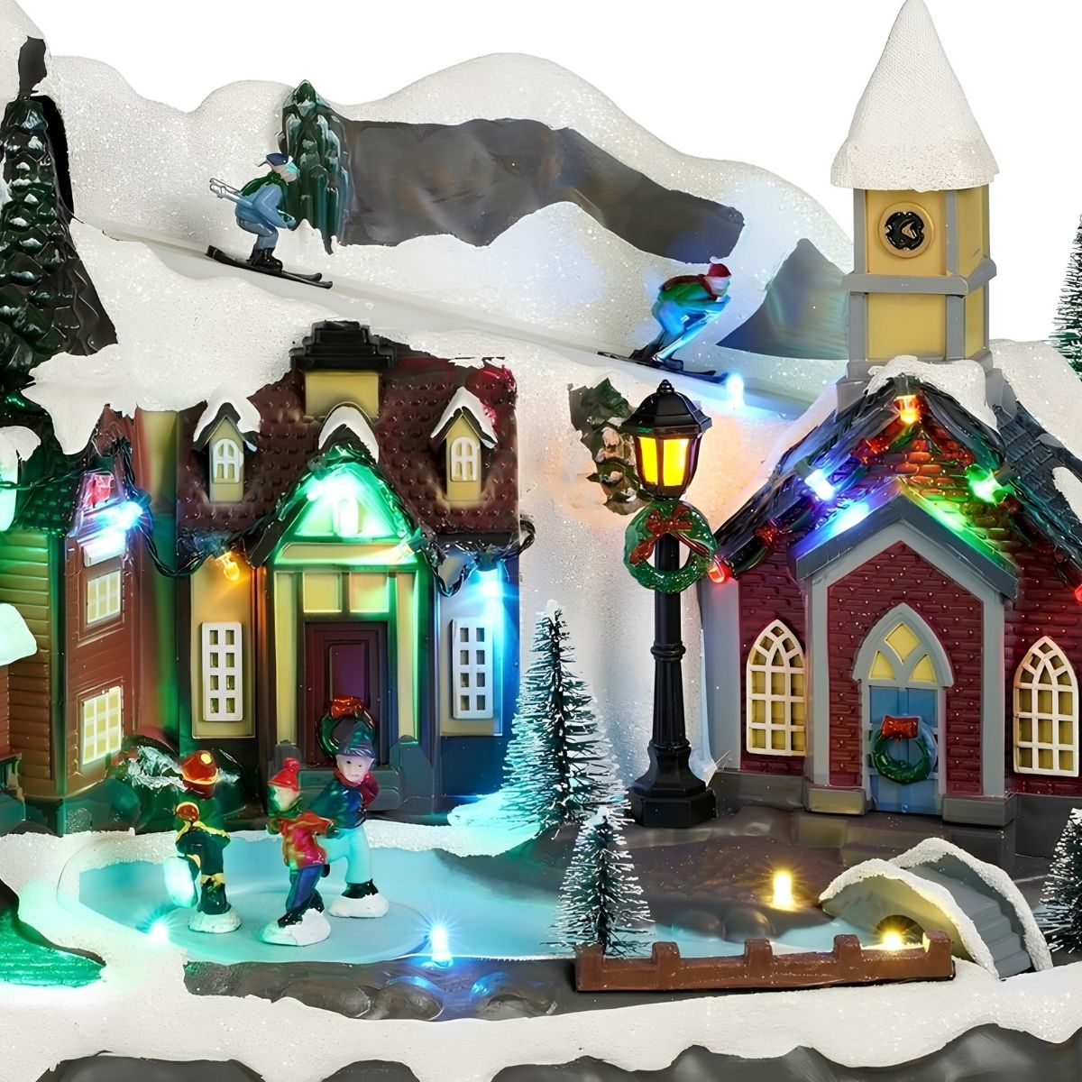 Verlicht kerstdorp met schaatsers, skiërs, een kerk en besneeuwde huizen.