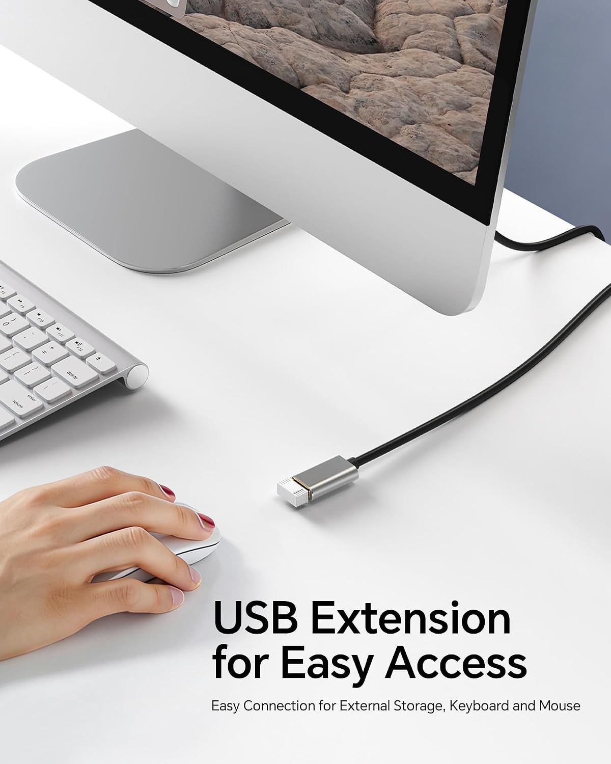 Hand bedient eine Maus auf weißem Schreibtisch neben Computer und USB-Kabel.