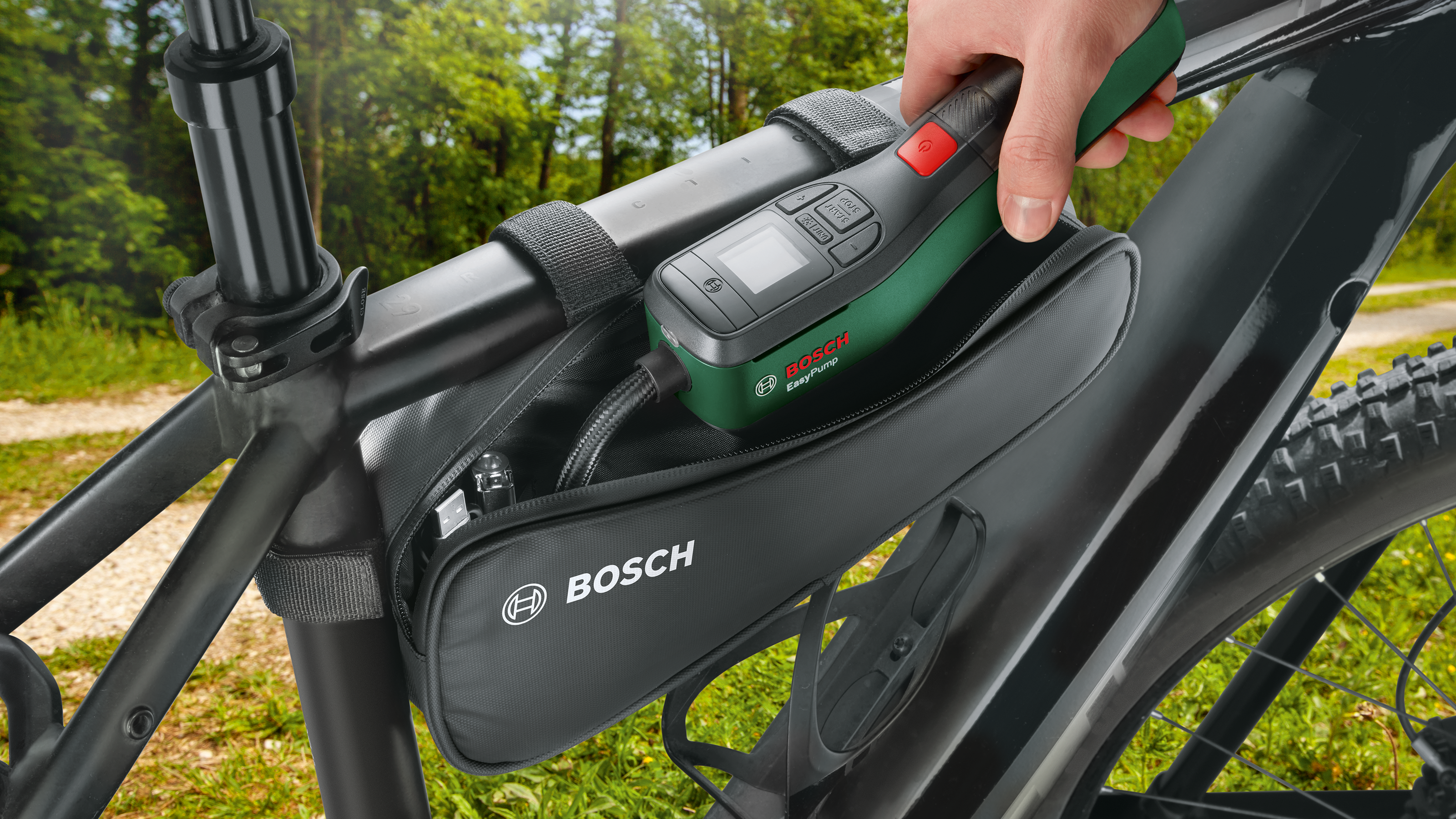 Eine Hand zieht eine grün-schwarze Bosch EasyPump aus einer schwarzen Rahmentasche an einem Fahrrad.