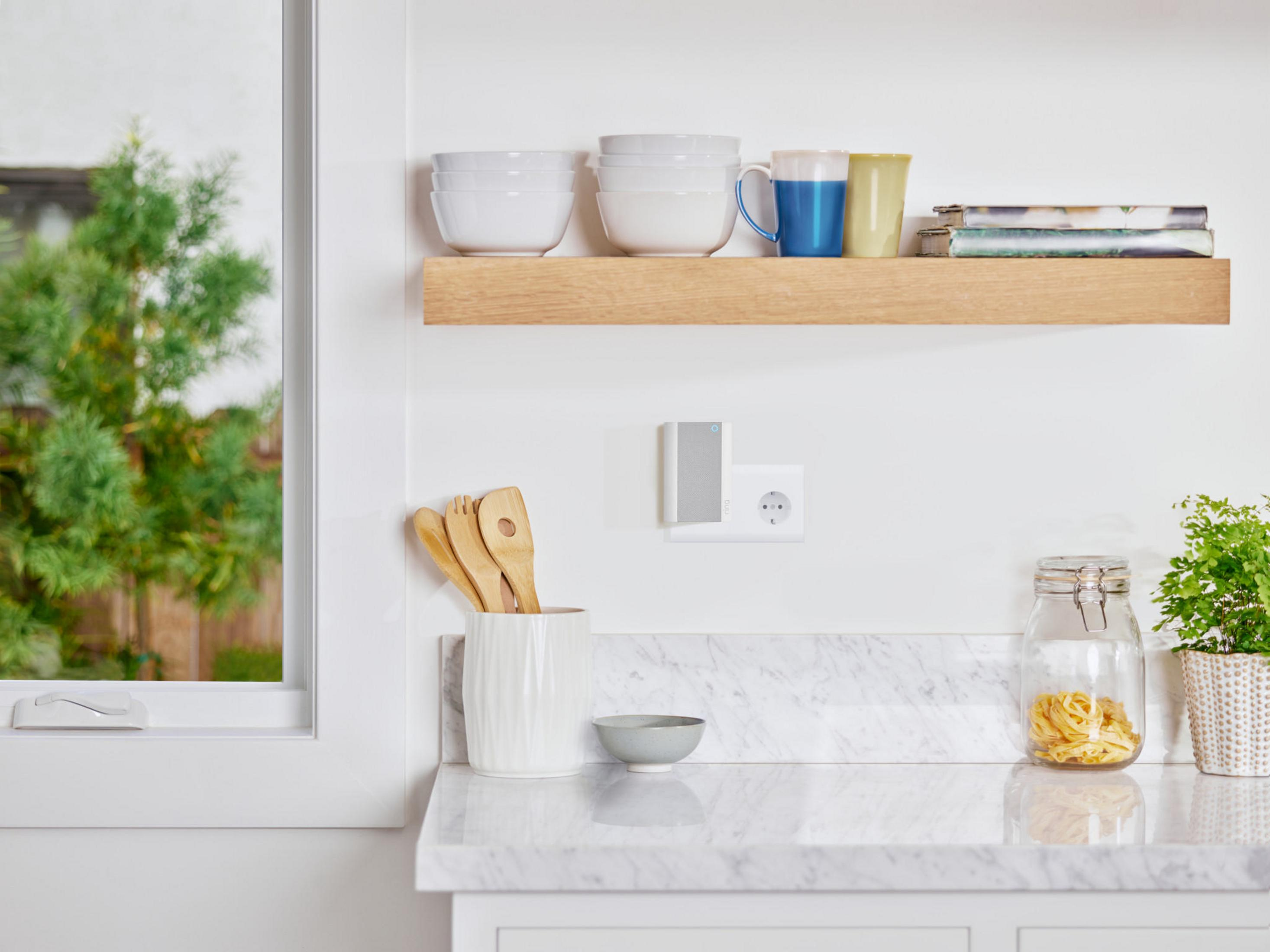Un comptoir de cuisine avec une étagère contenant bols et tasses. Un appareil est branché.
