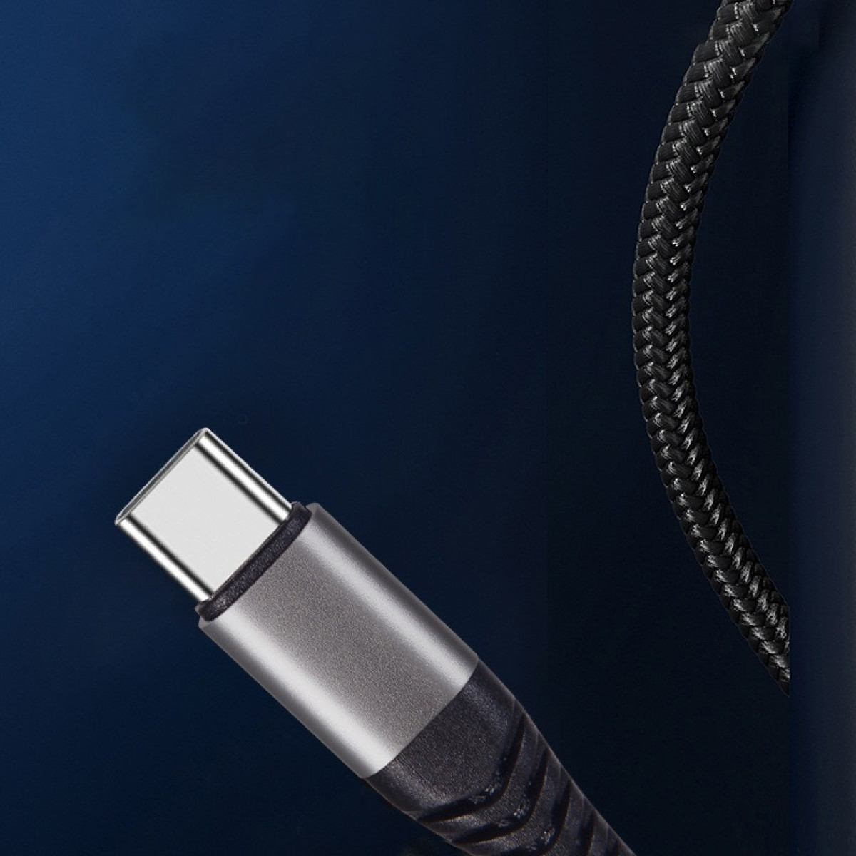 Nahaufnahme eines silbernen USB-C-Steckers an einem geflochtenen schwarzen Kabel vor dunklem Hintergrund.