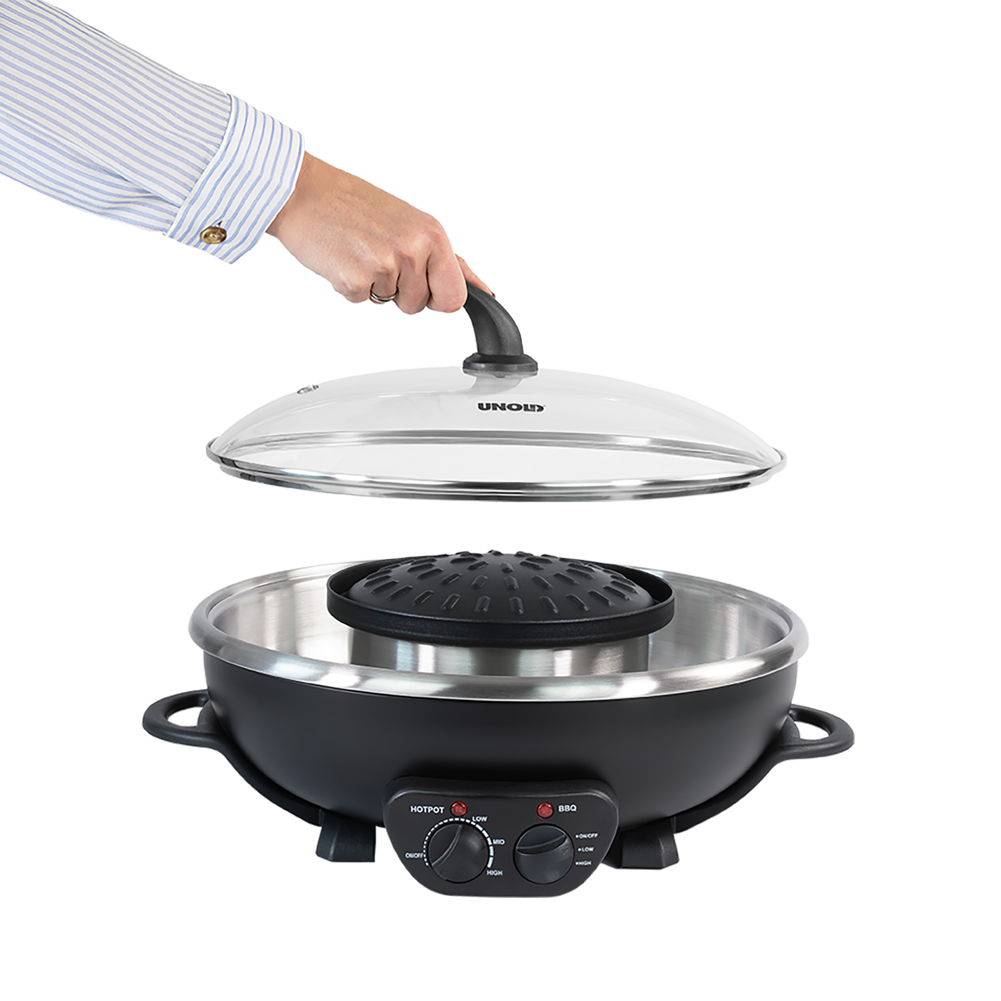 Eine Hand hält den Glasdeckel eines elektrischen Tischgrills mit schwarzem Gehäuse und silbernem Einsatz.