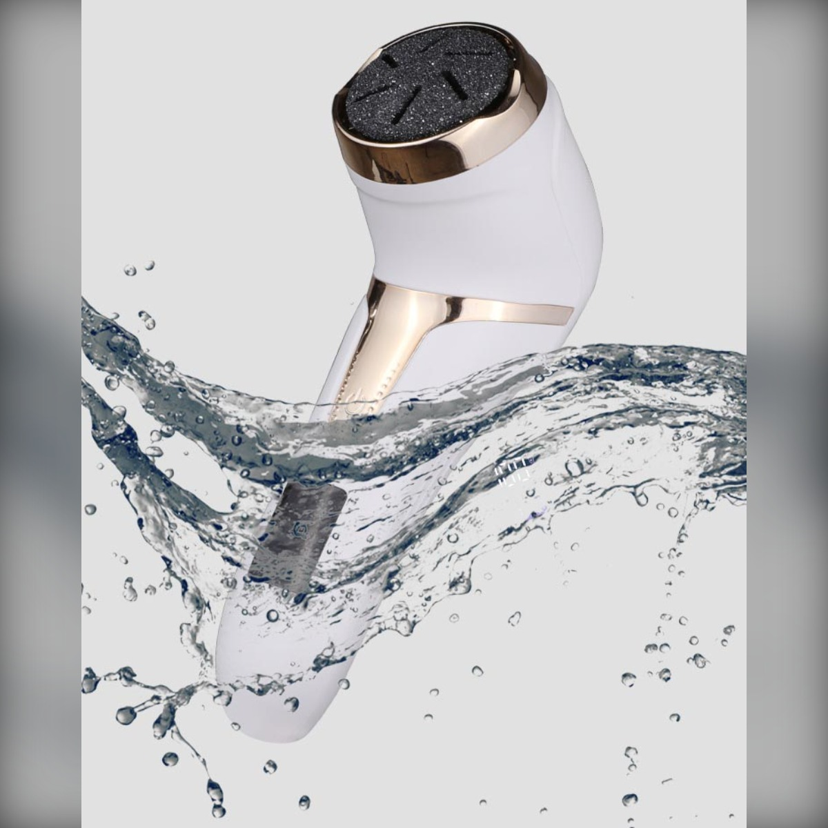Eine weiß-goldene elektrische Hornhautfeile taucht auf grauem Hintergrund in spritzendes Wasser.