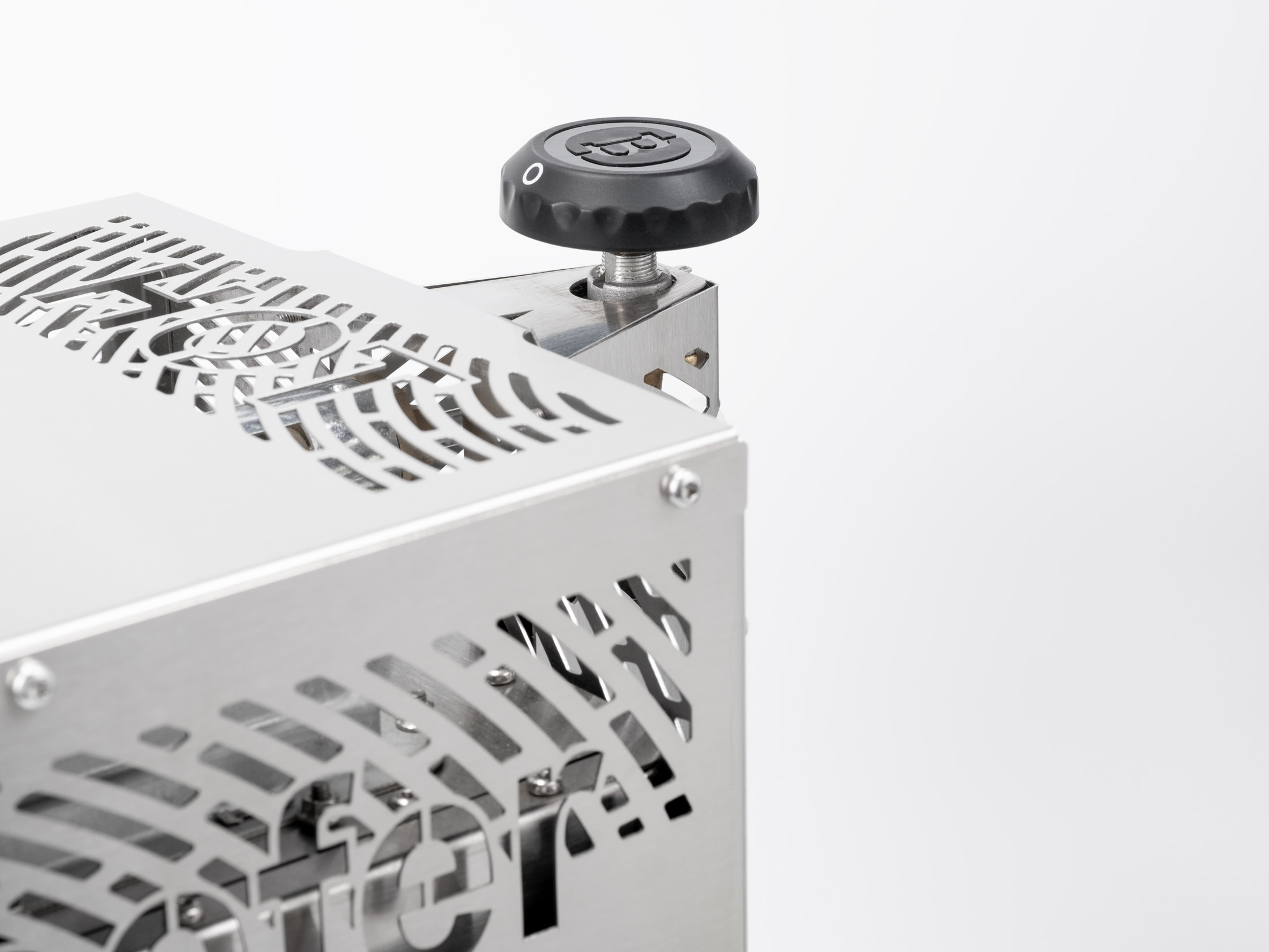 Nahaufnahme einer Metallmaschine mit Perforationen und einem schwarzen Drehknopf auf weißem Hintergrund.