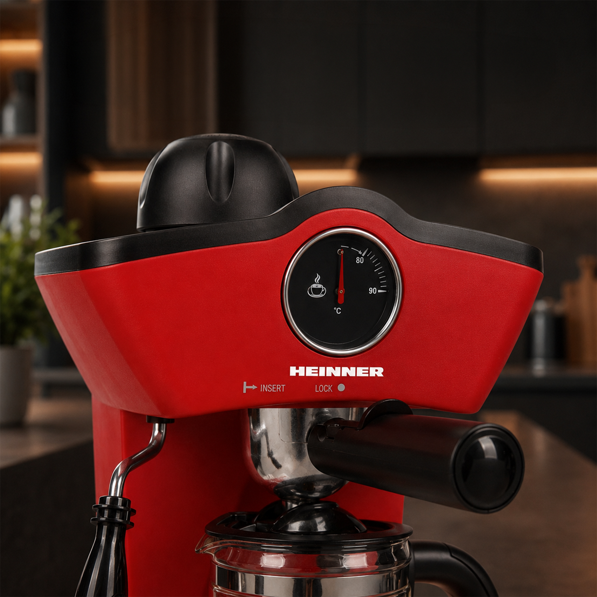Machine à espresso Heinner rouge avec poignée noire et jauge de température ronde dans une cuisine.