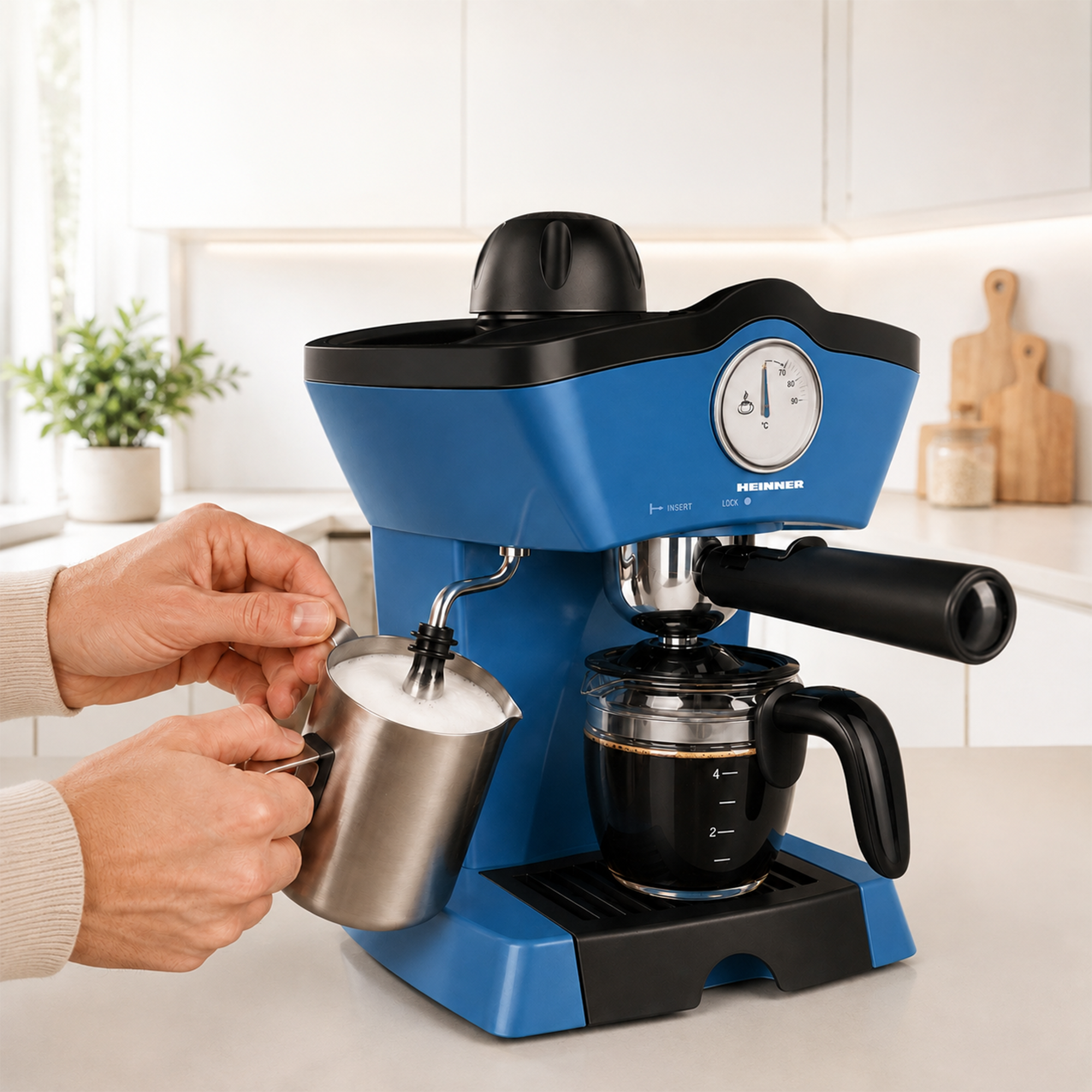 Eine Hand schäumt Milch in einem Metallkrug neben einer blauen Espressomaschine in einer Küche.