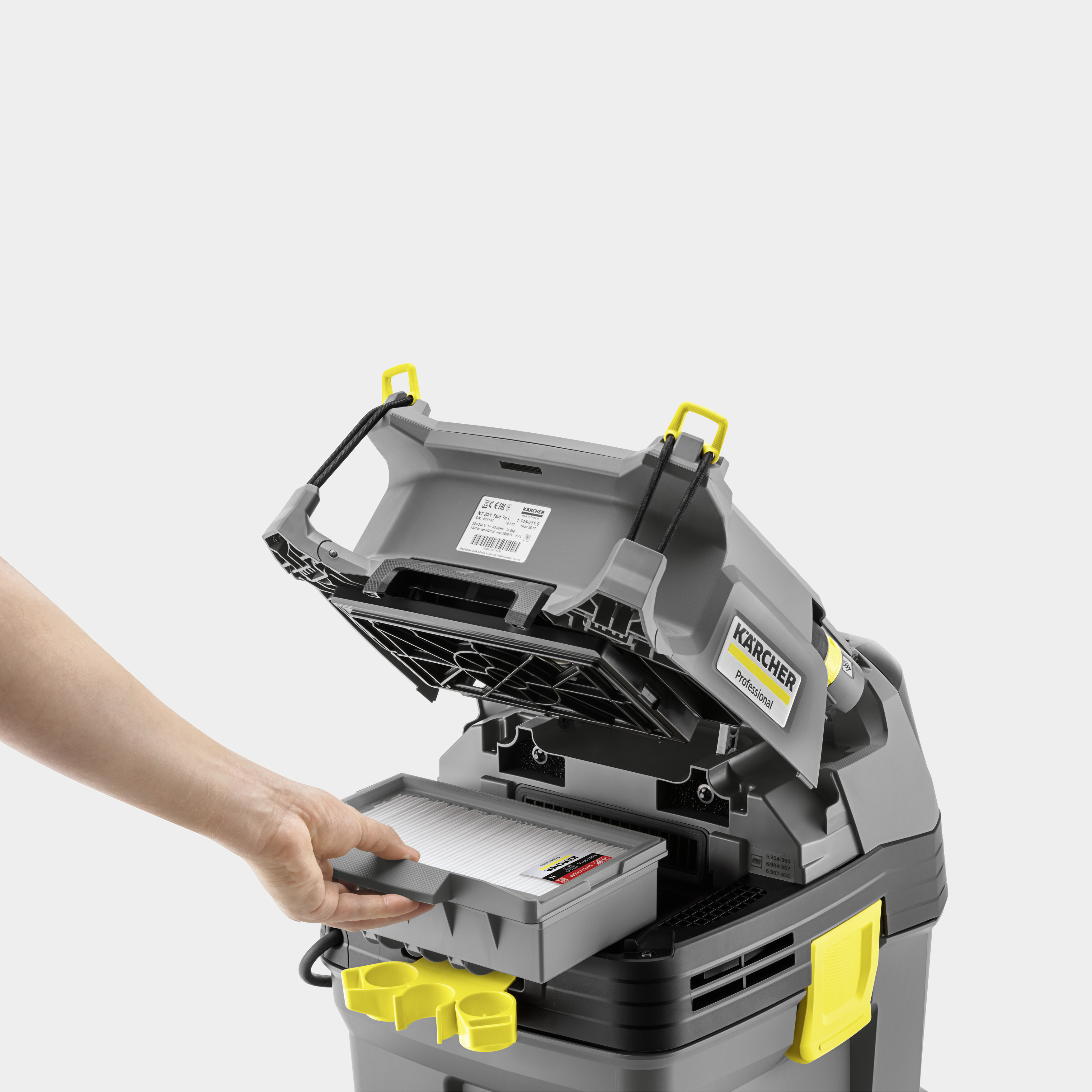 Eine Hand nimmt den grauen Filter aus einer geöffneten Kärcher-Maschine.